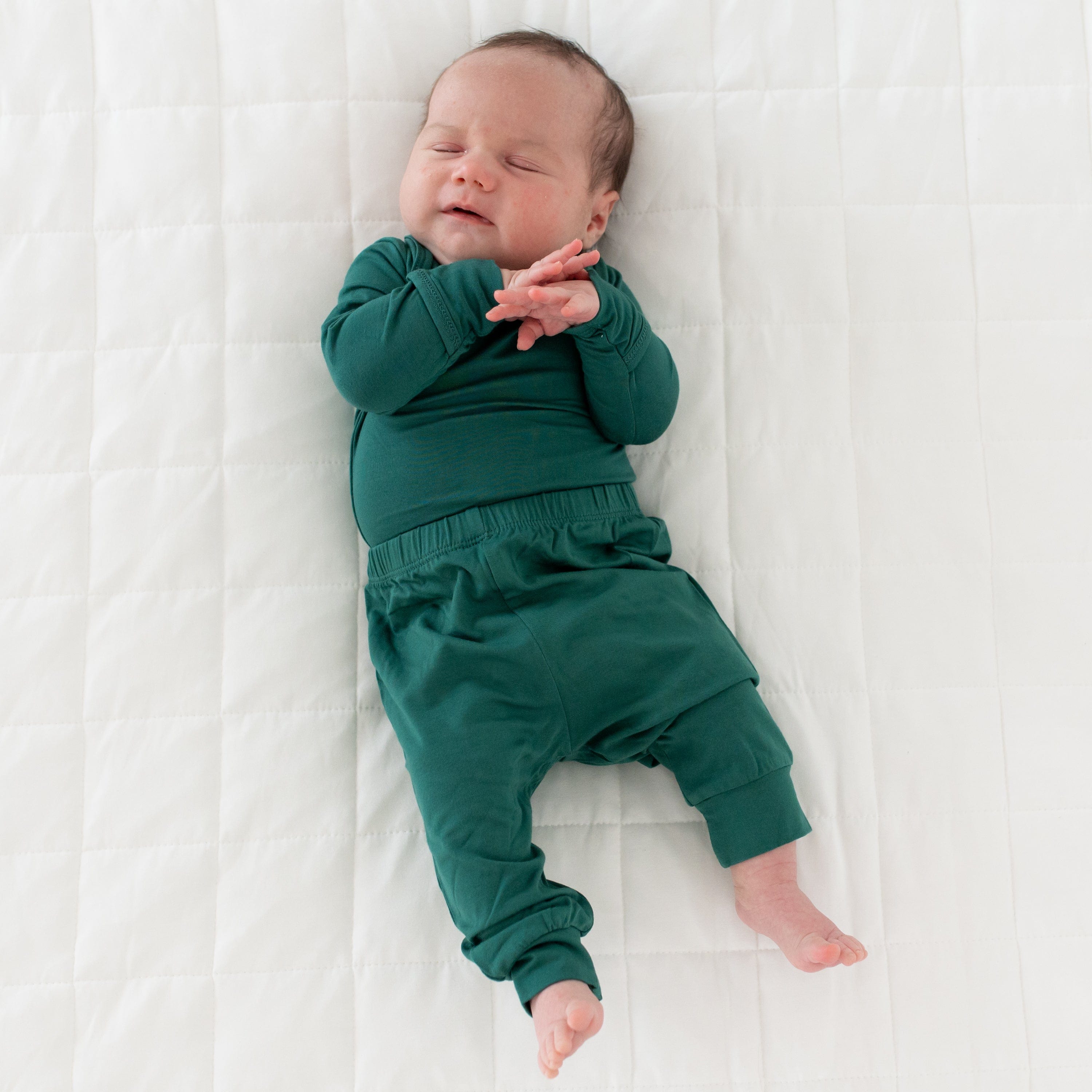 Sleeping infant holding hands and wearing Long Sleeve Bodysuit in Emerald