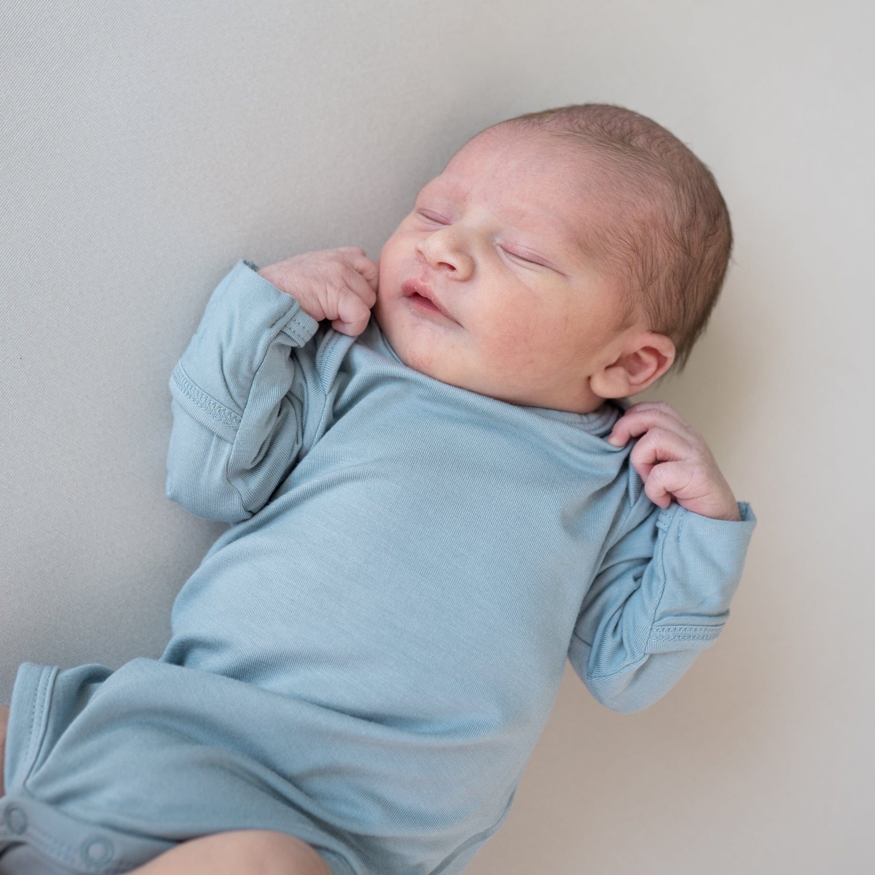 Newborn wearing Kyte Baby Long Sleeve Bodysuit in Fog