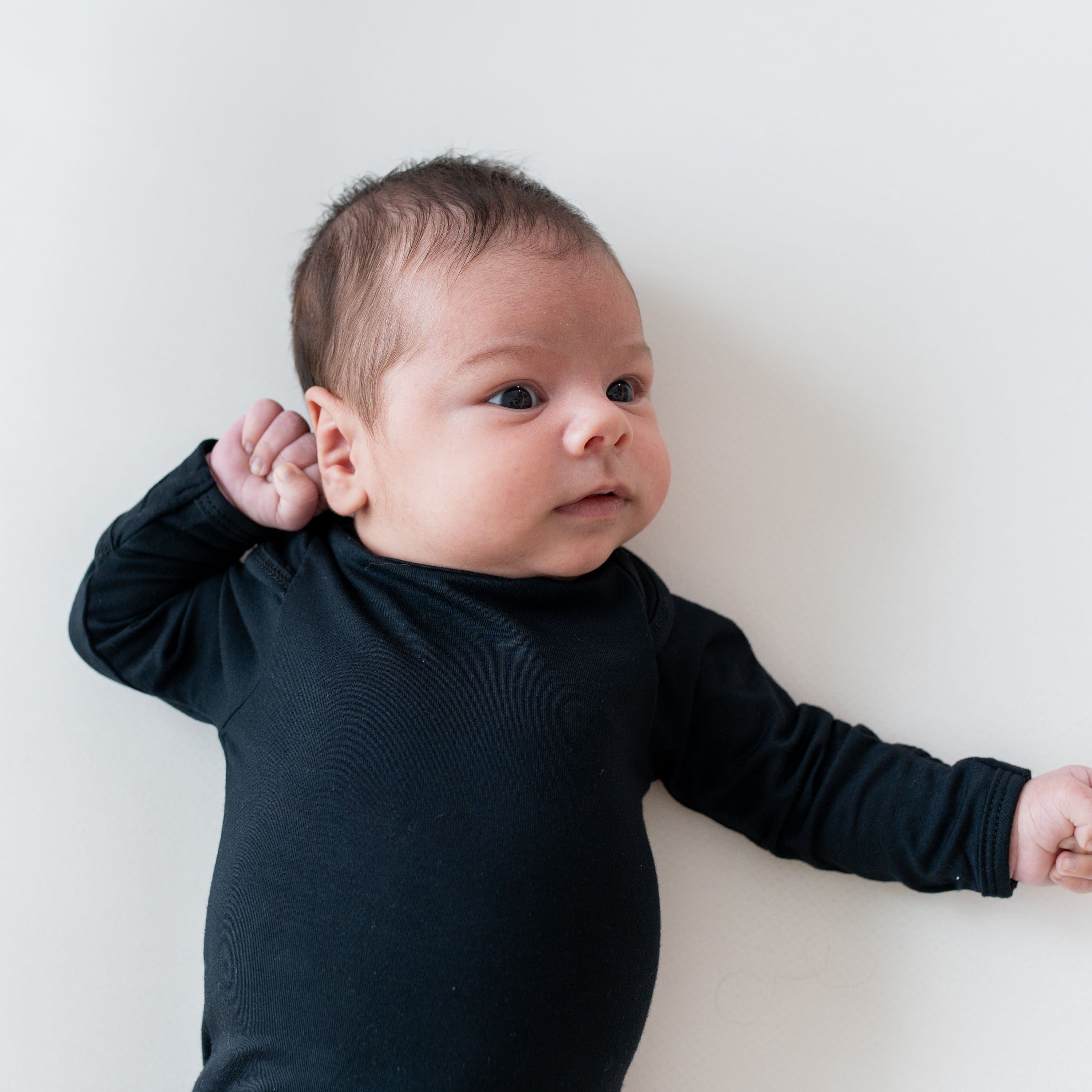 Close up of newborn wearing Kyte Baby Long Sleeve Bodysuit in Midnight