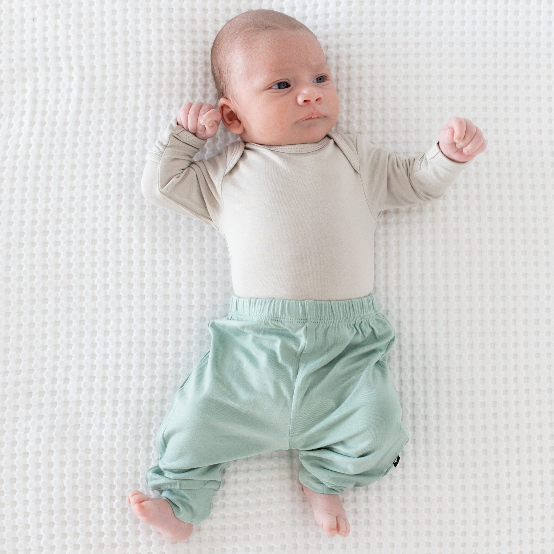 Baby wearing Kyte Baby Long Sleeve infant Bodysuit in Oat