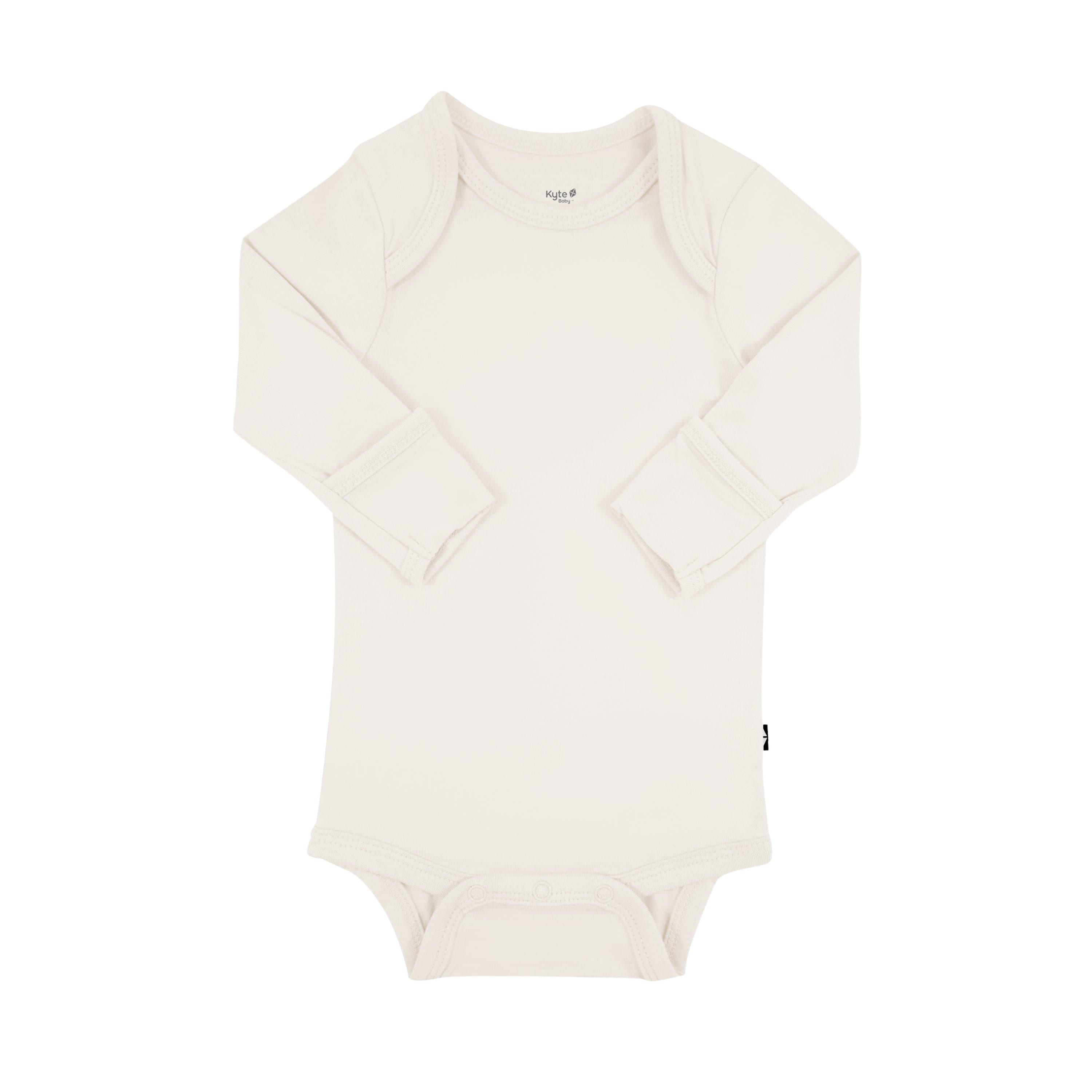 Flat lay of Kyte Baby Long Sleeve Bodysuit in Oat with arms folded inwards displaying fold-over cuffs
