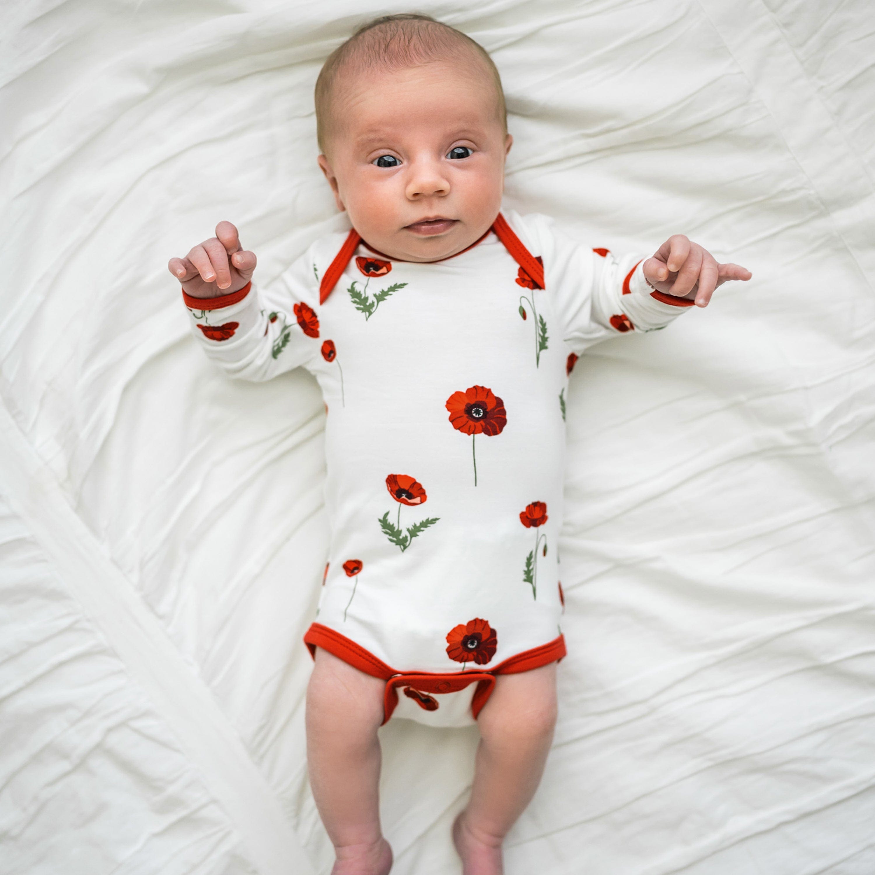 Infant wearing Kyte Baby Long Sleeve infant Bodysuit in Cloud Poppies
