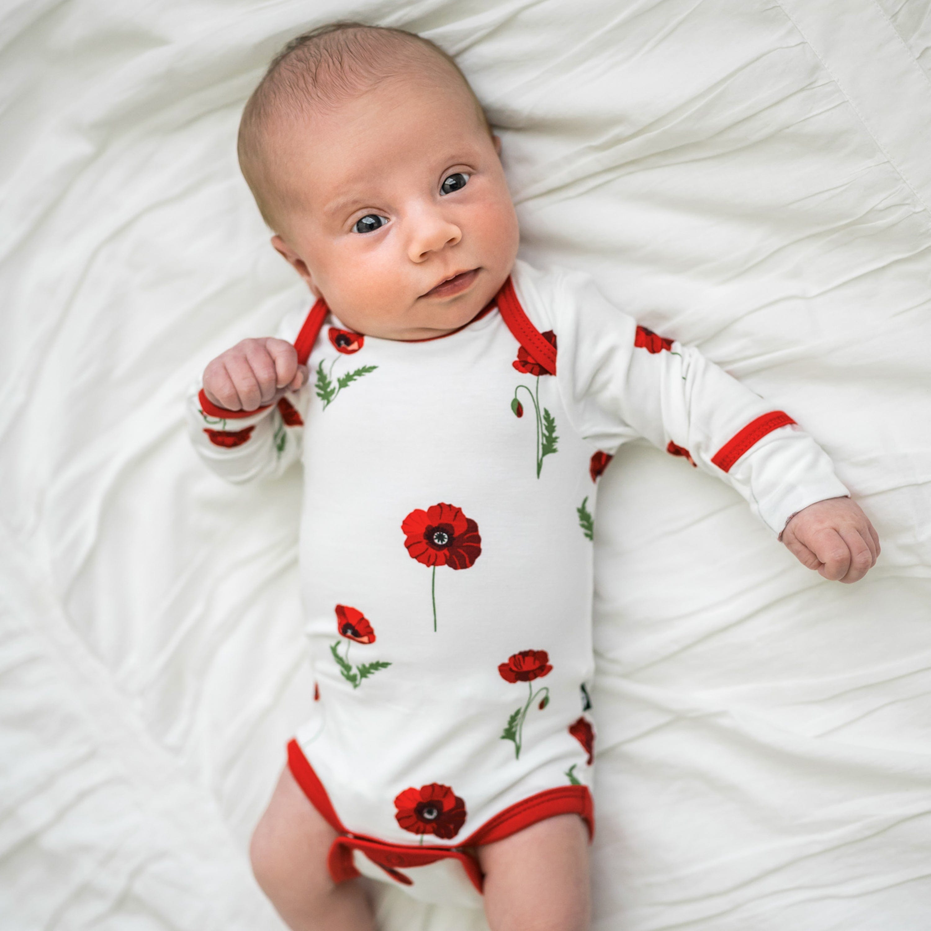 Newborn wearing Kyte Baby Long Sleeve Infant Bodysuit in Cloud Poppies