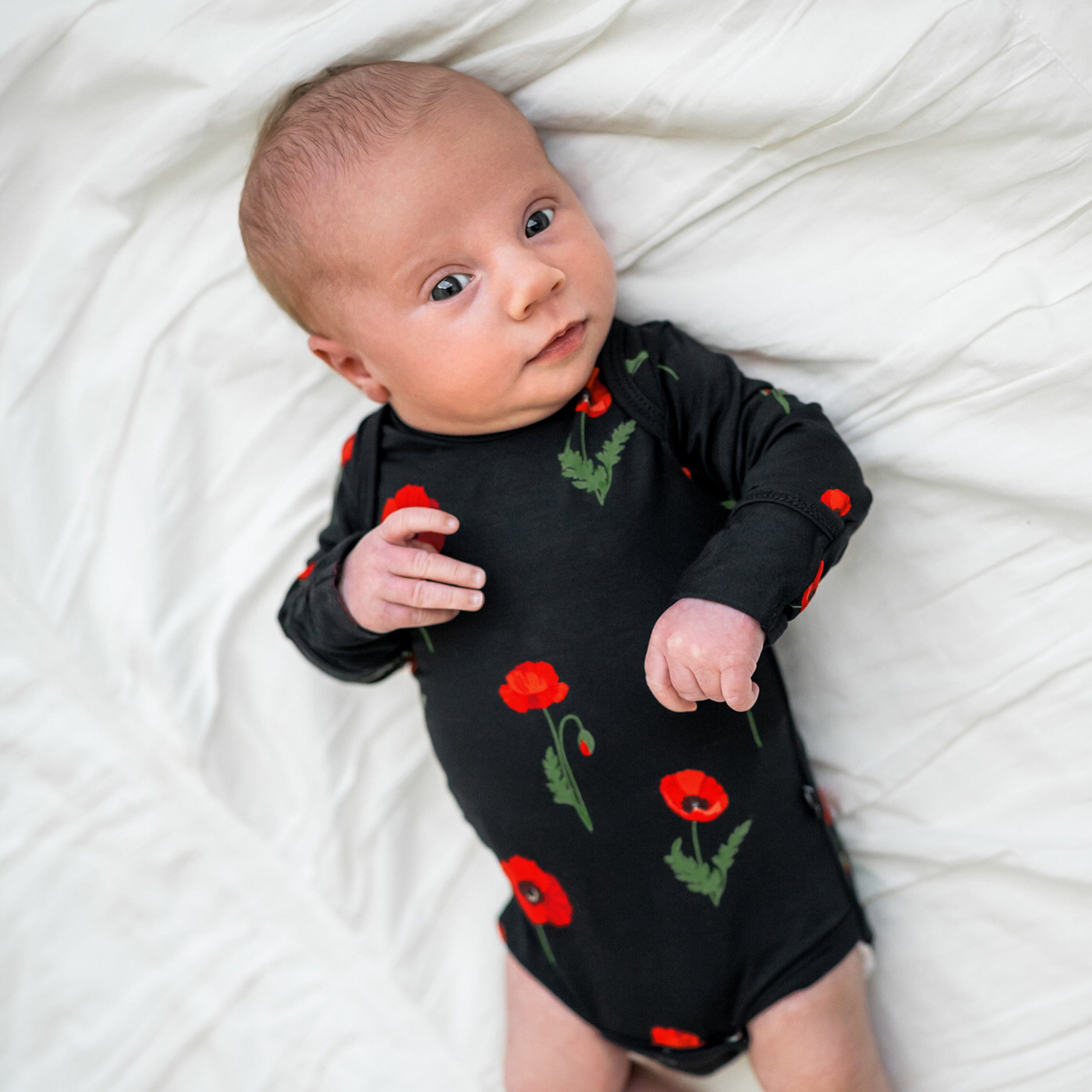 Newborn wearing Kyte Baby Long Sleeve infant Bodysuit in Midnight Poppies