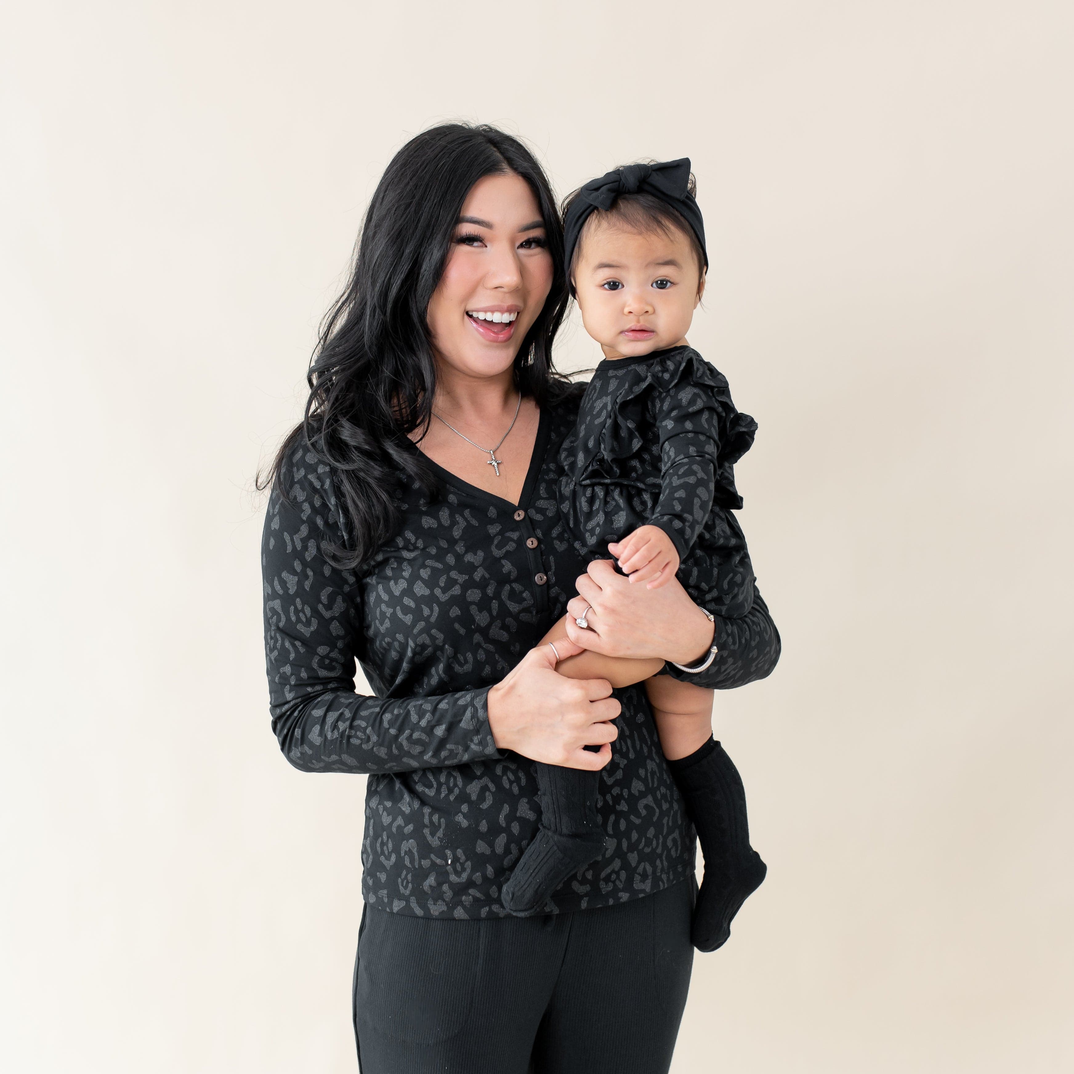 Mom wearing Henley Tee holding Toddler wearing Kyte Baby Long Sleeve Bubble Romper in Midnight Leopard