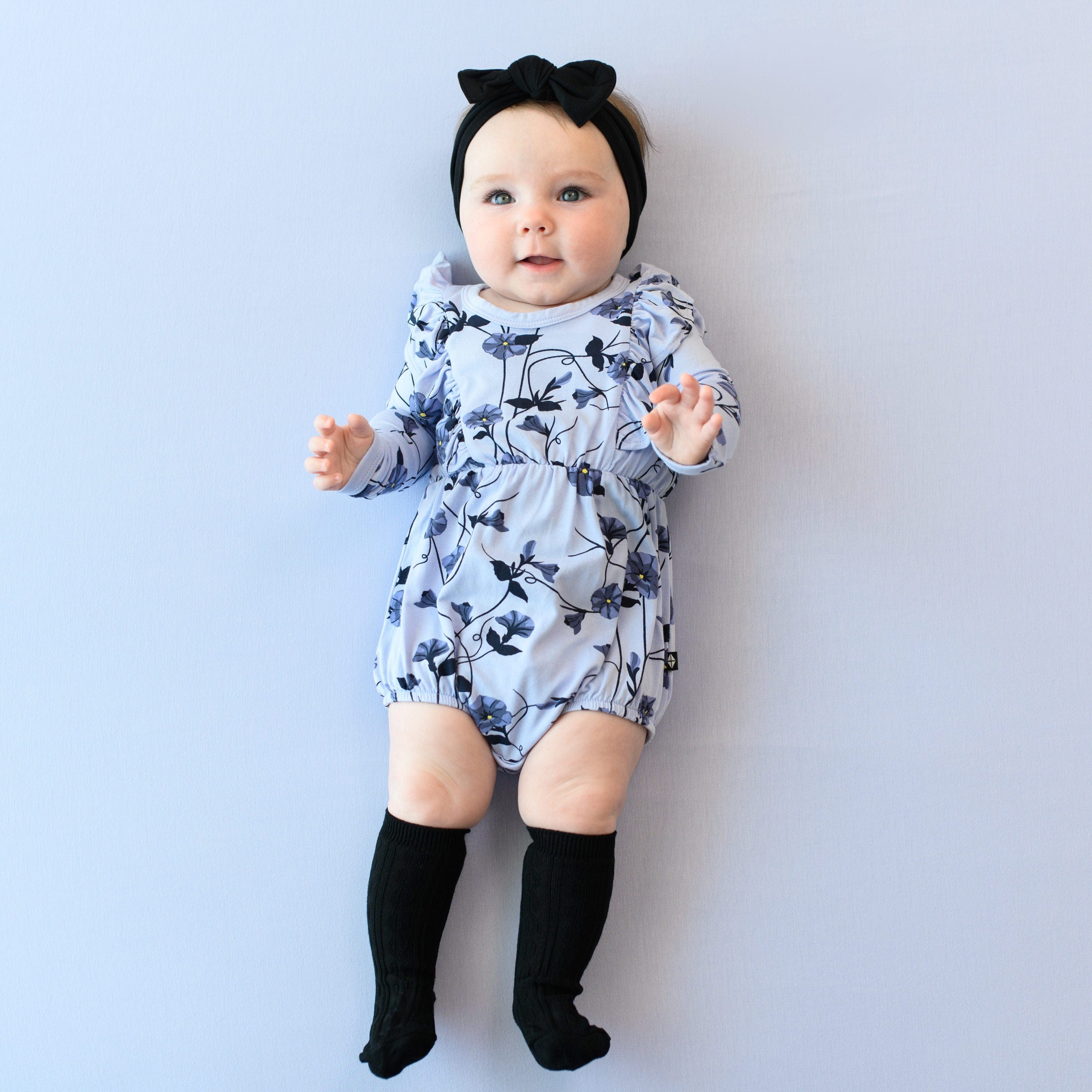 Infant wearing Kyte Baby Long Sleeve Bubble Romper with ruffles in Petunia