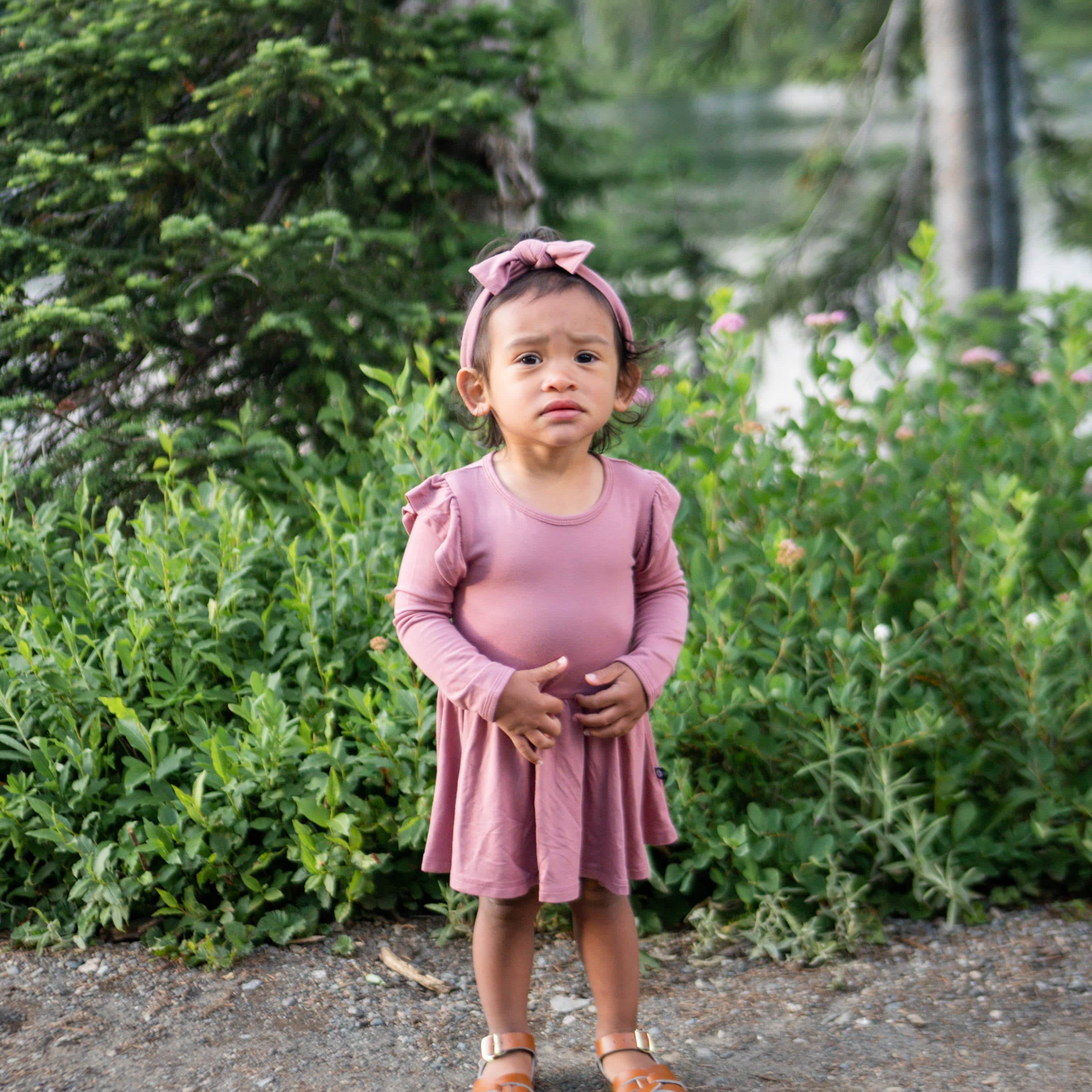 Girl wearing Kyte Baby bamboo Long Sleeve Twirl Bodysuit Dress in Dusty Rose