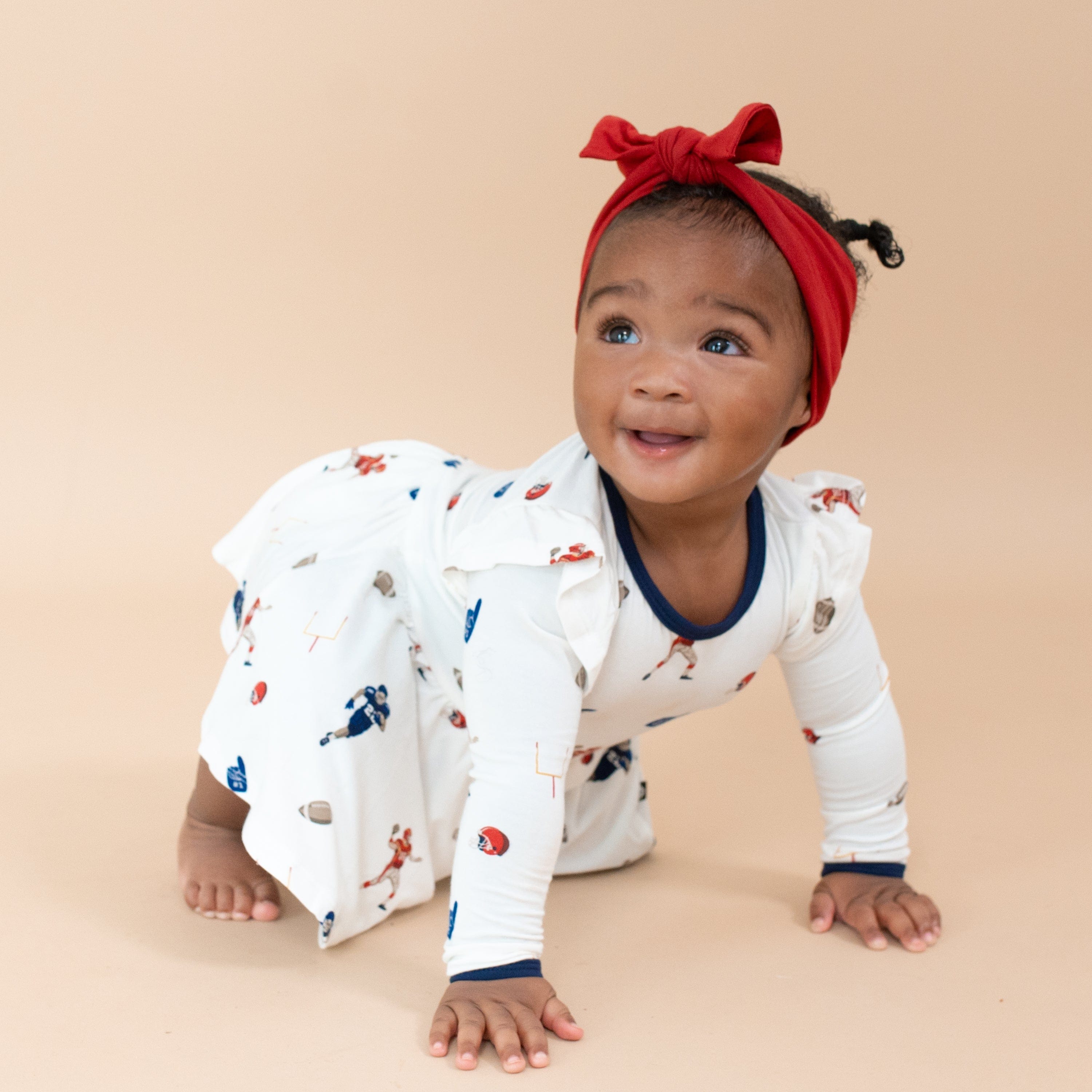 Child wearing Kyte Baby Bodysuit with Twirl Skirt in Football