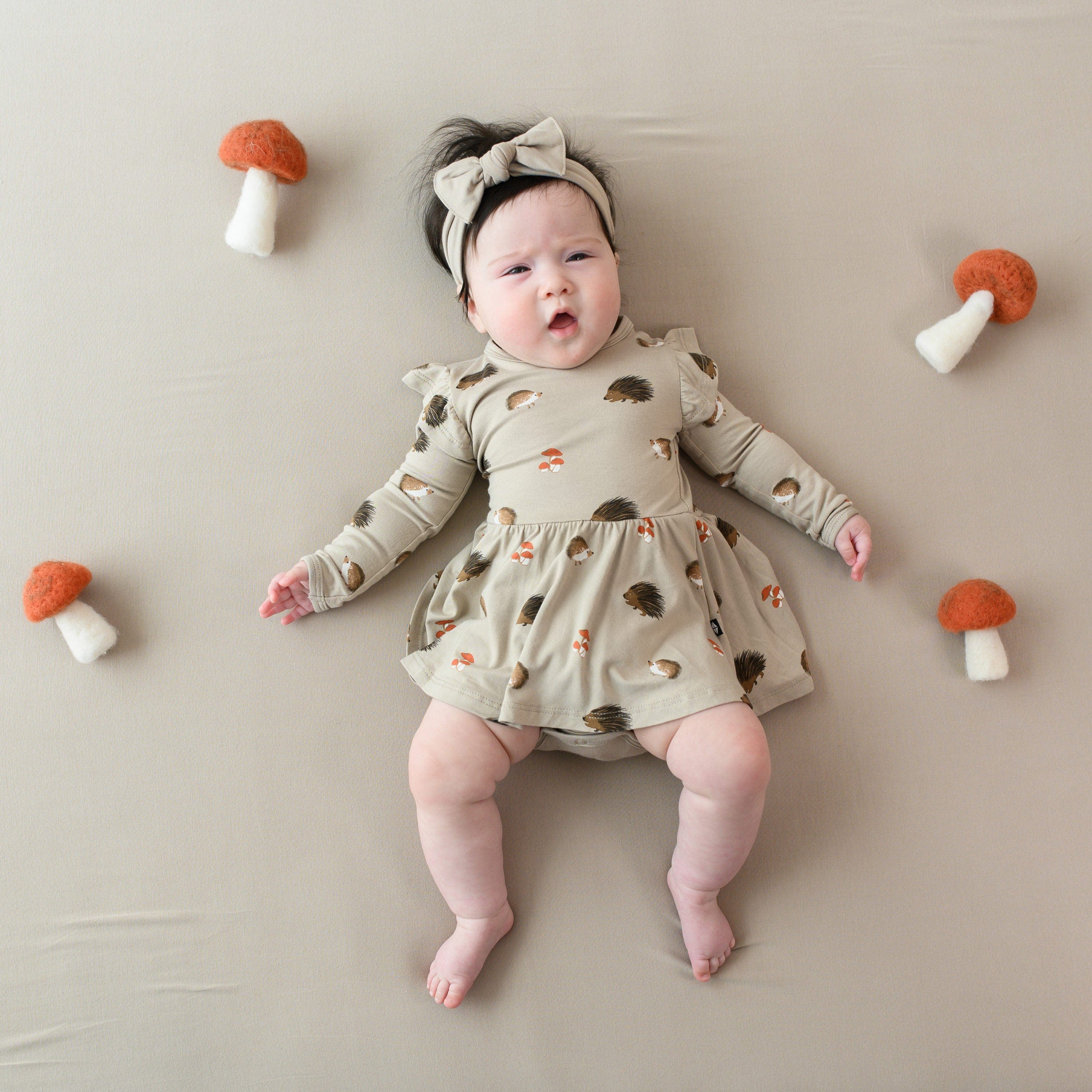 Infant wearing Kyte Baby Twirl Bodysuit Dress in Prickle