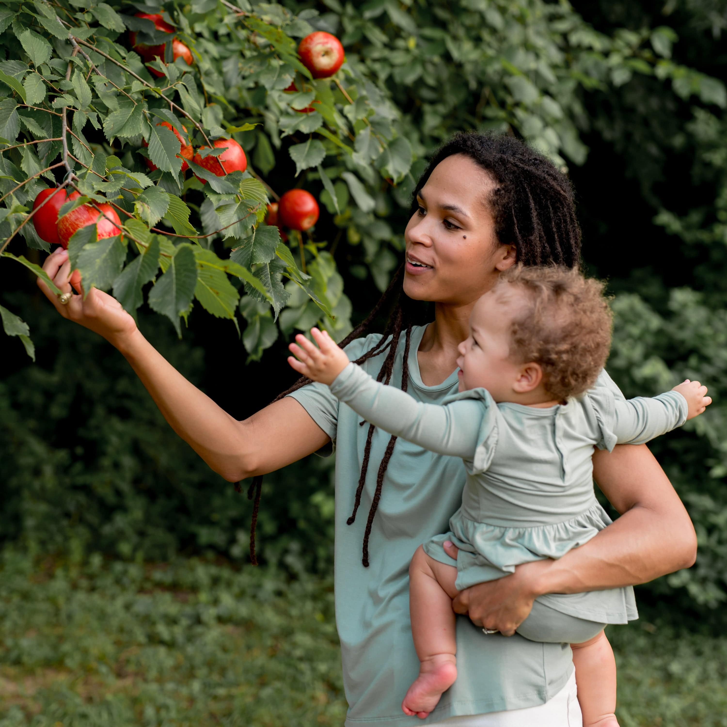 Mom holding Toddler wearing bamboo Kyte Baby Twirl Bodysuit in Thyme green
