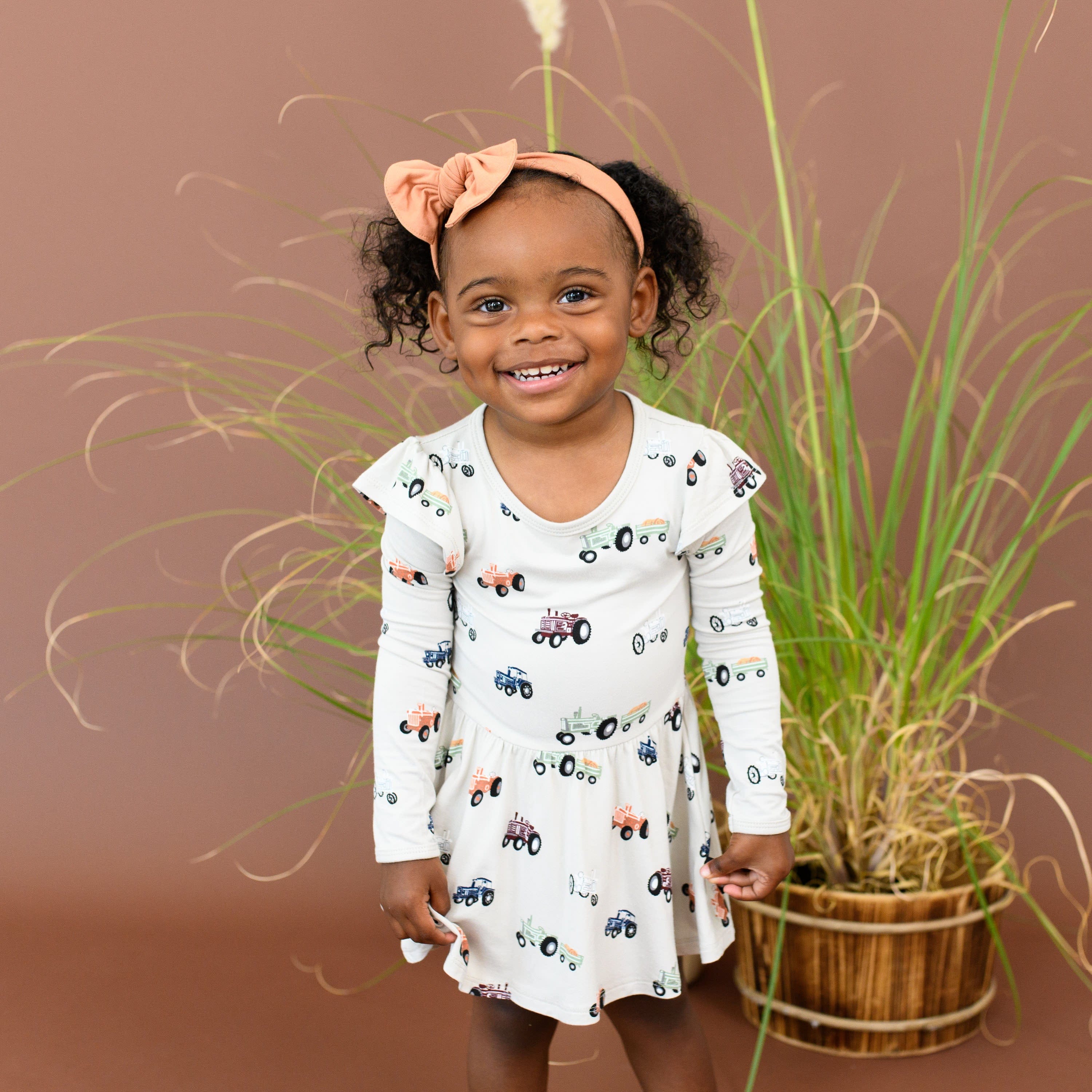 Child wearing Kyte Baby Bodysuit with Twirl Skirt in Tractor