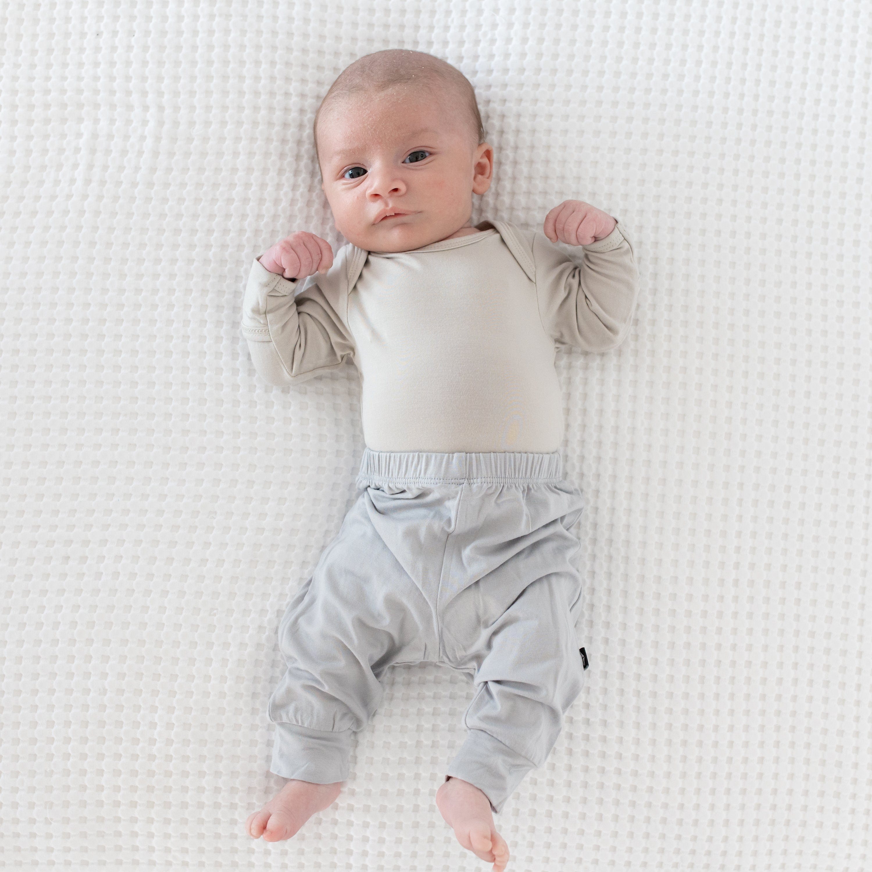 Newborn wearing Kyte Baby Pants in Storm an Long Sleeve Bodysuit in Oat
