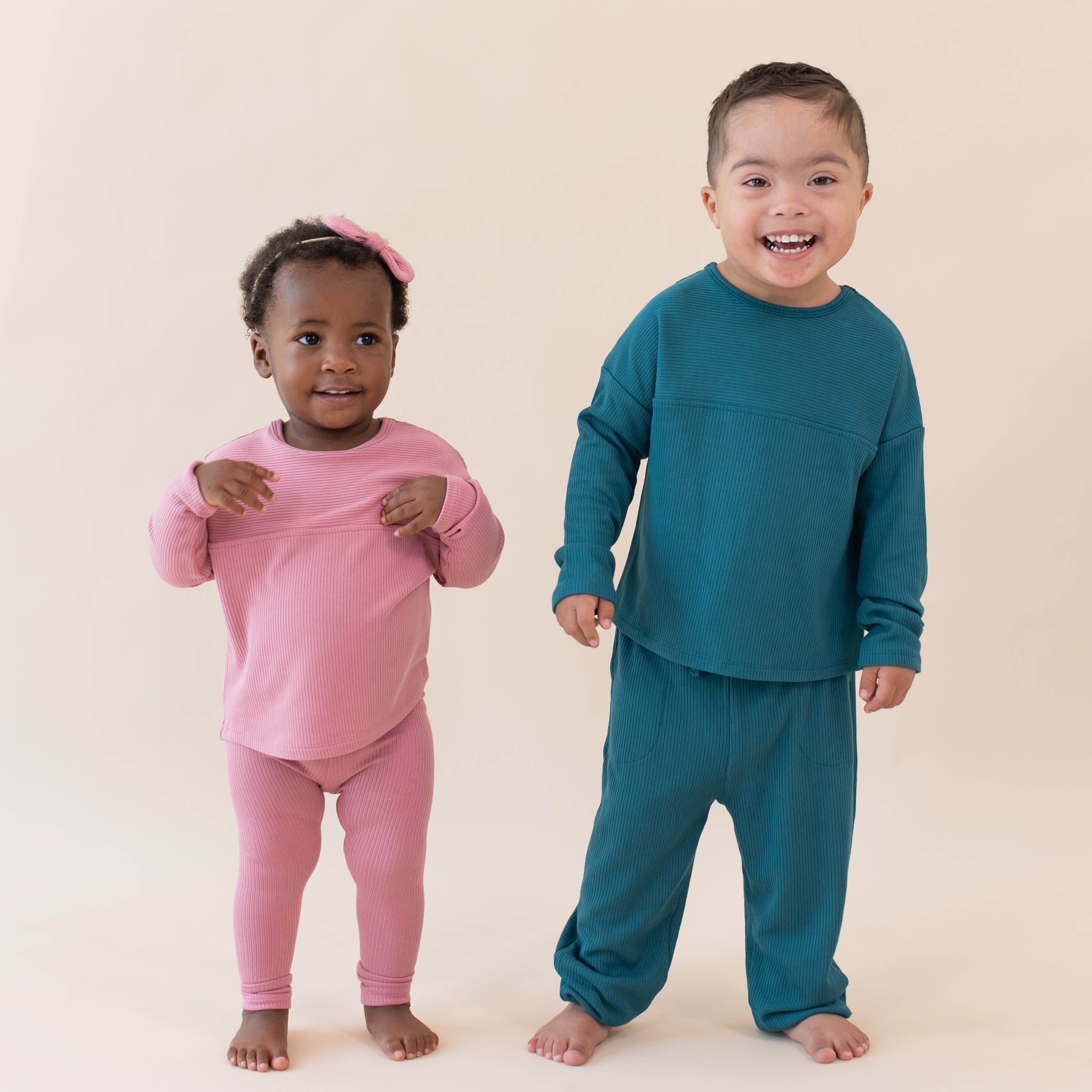 Toddlers wearing Kyte Baby Bamboo Ribbed Drop Shoulder Tops in Apple Blossom and Loch
