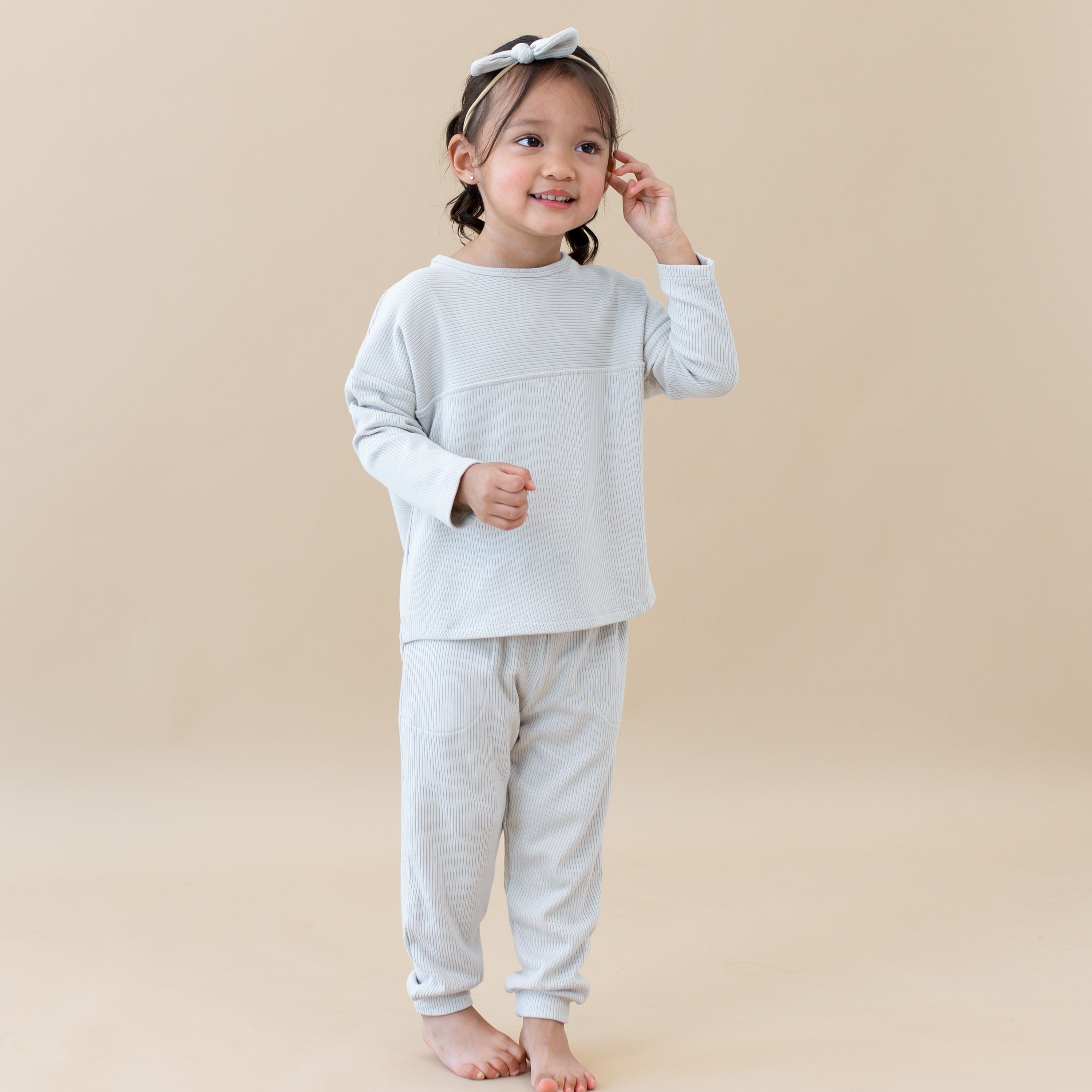 Toddler wearing Kyte Baby Top with Drop Shoulder and Curved Hem in Oat