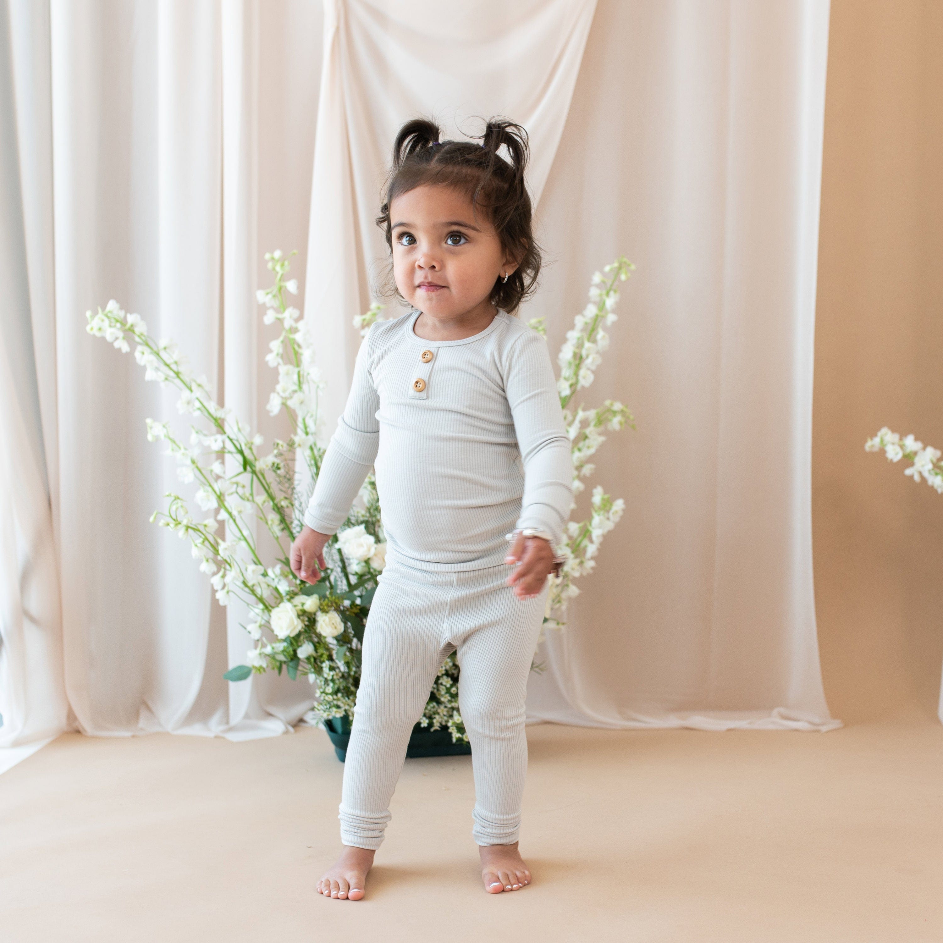 Toddler wearing Kyte Baby Ribbed Henley Set with wooden button placket in Oat