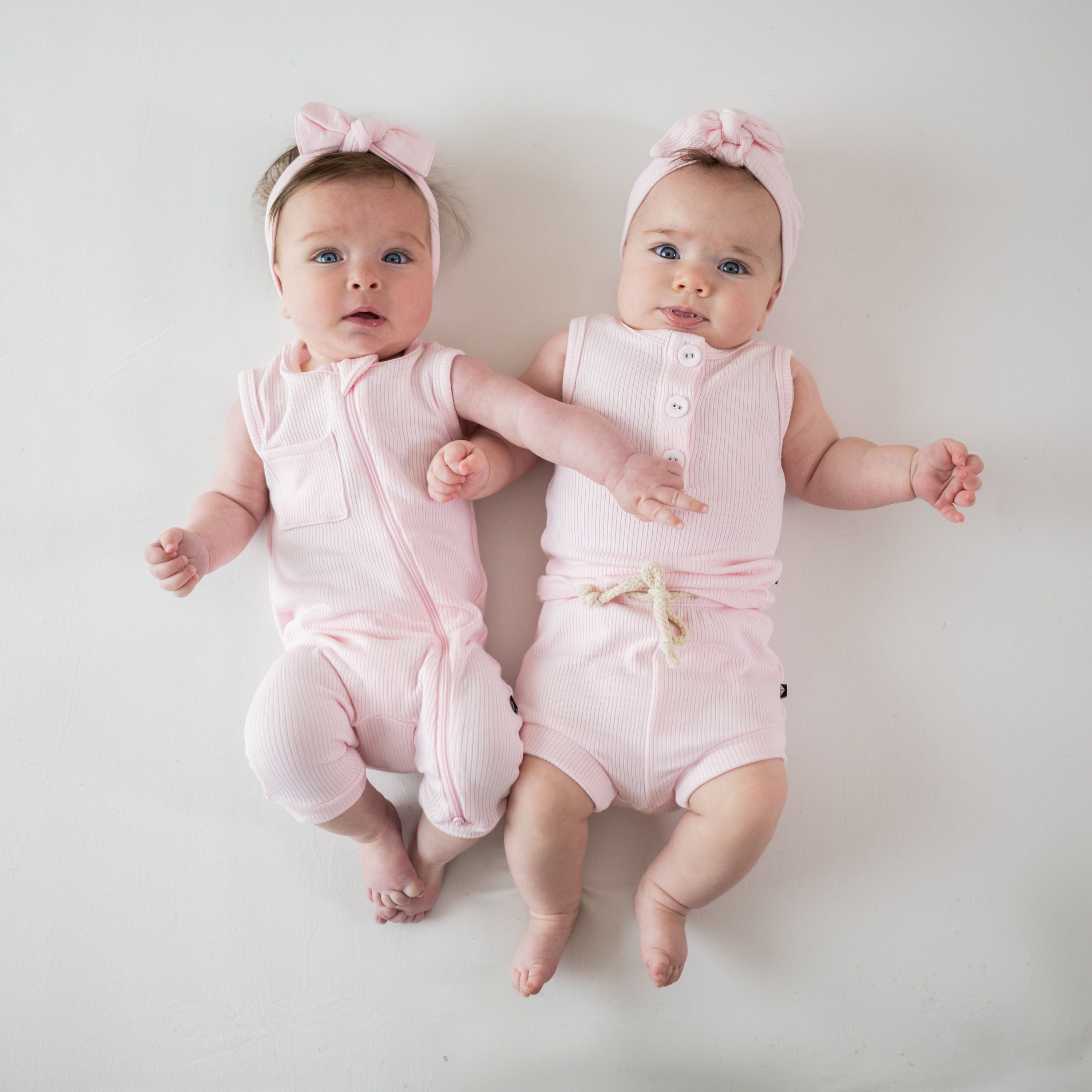 Babies wearing Kyte Baby bamboo ribbed outfits in Sakura pink