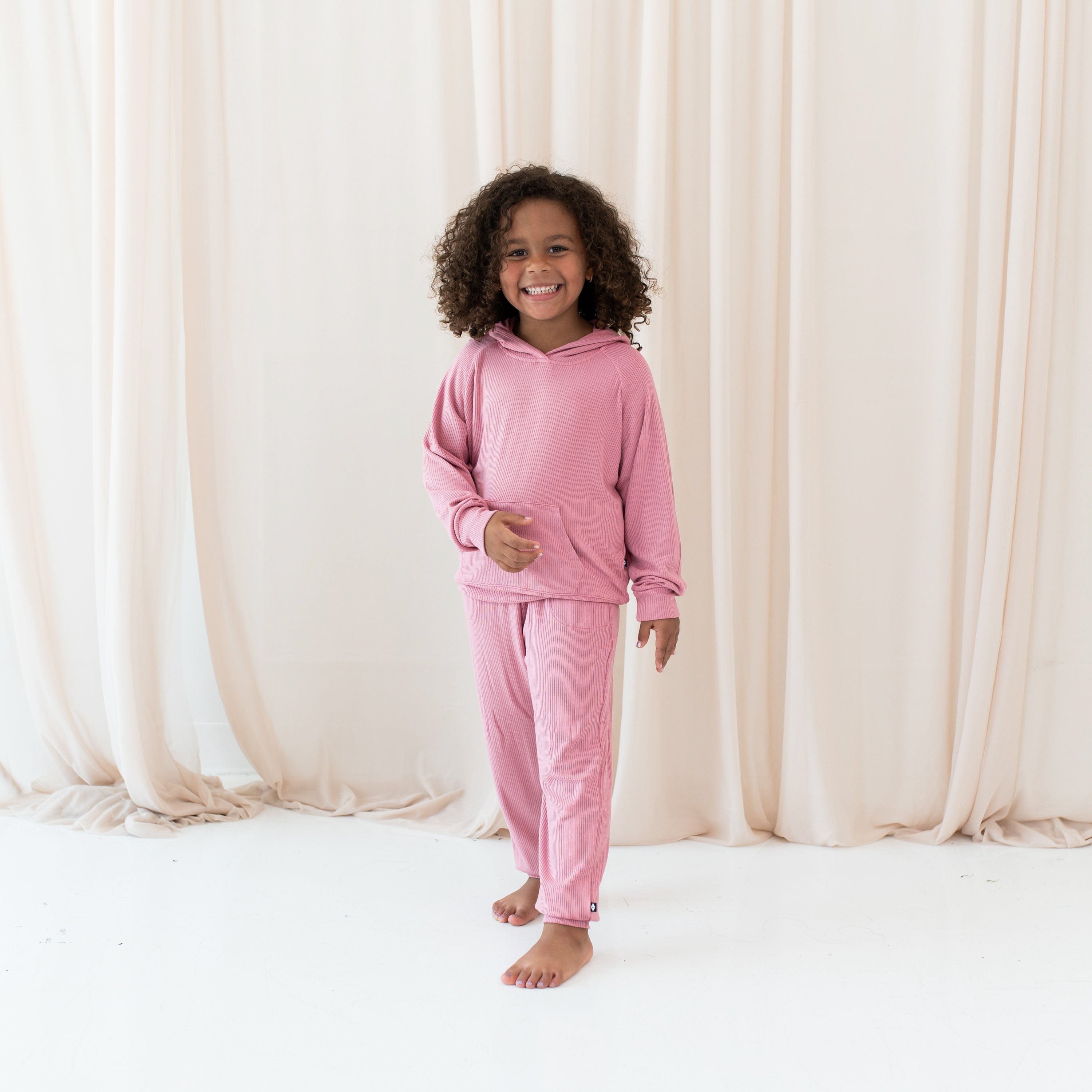 Girl wearing Kyte Baby bamboo Ribbed Jogger Pant and Hoodie in Apple Blossom