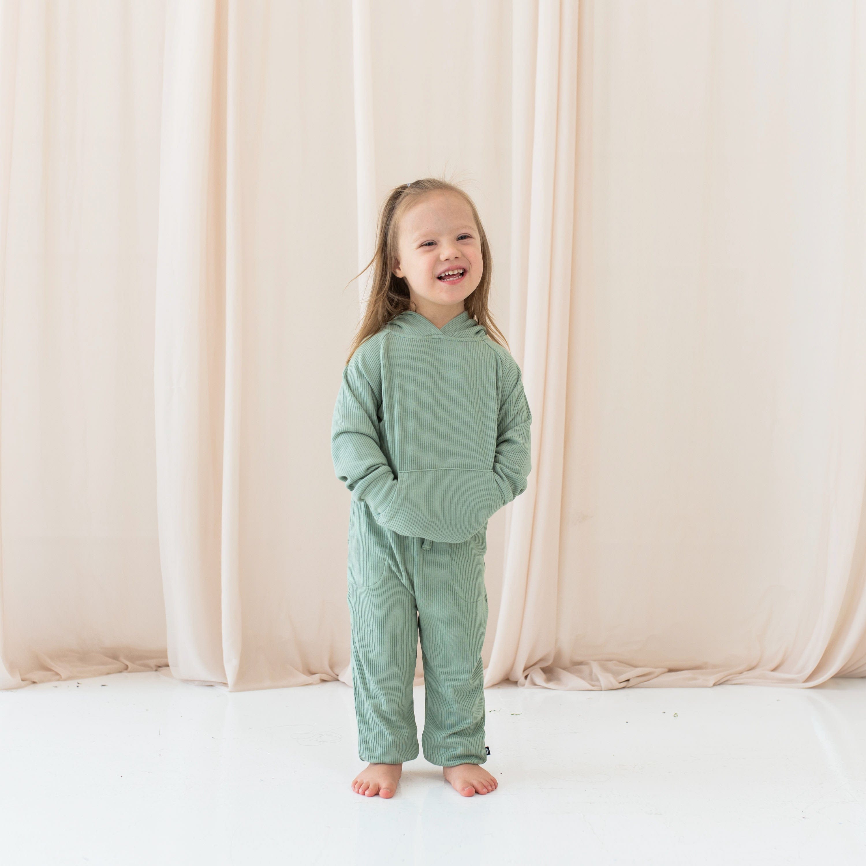 Girl wearing Kyte Baby Ribbed Hoodie with kangaroo pocket and Jogger Pant in Thyme