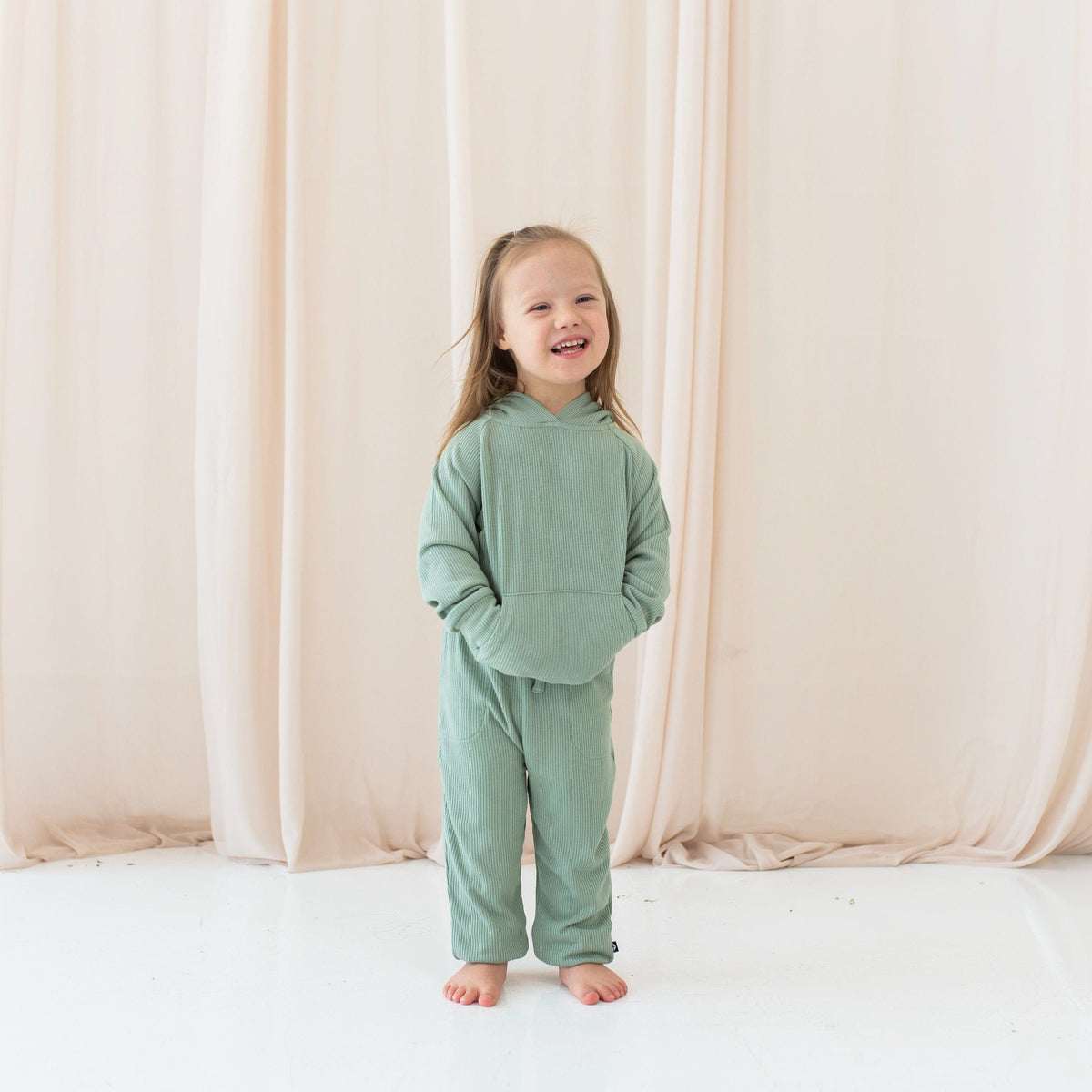Girl wearing Kyte Baby Ribbed Hoodie with kangaroo pocket and Jogger Pant in Thyme
