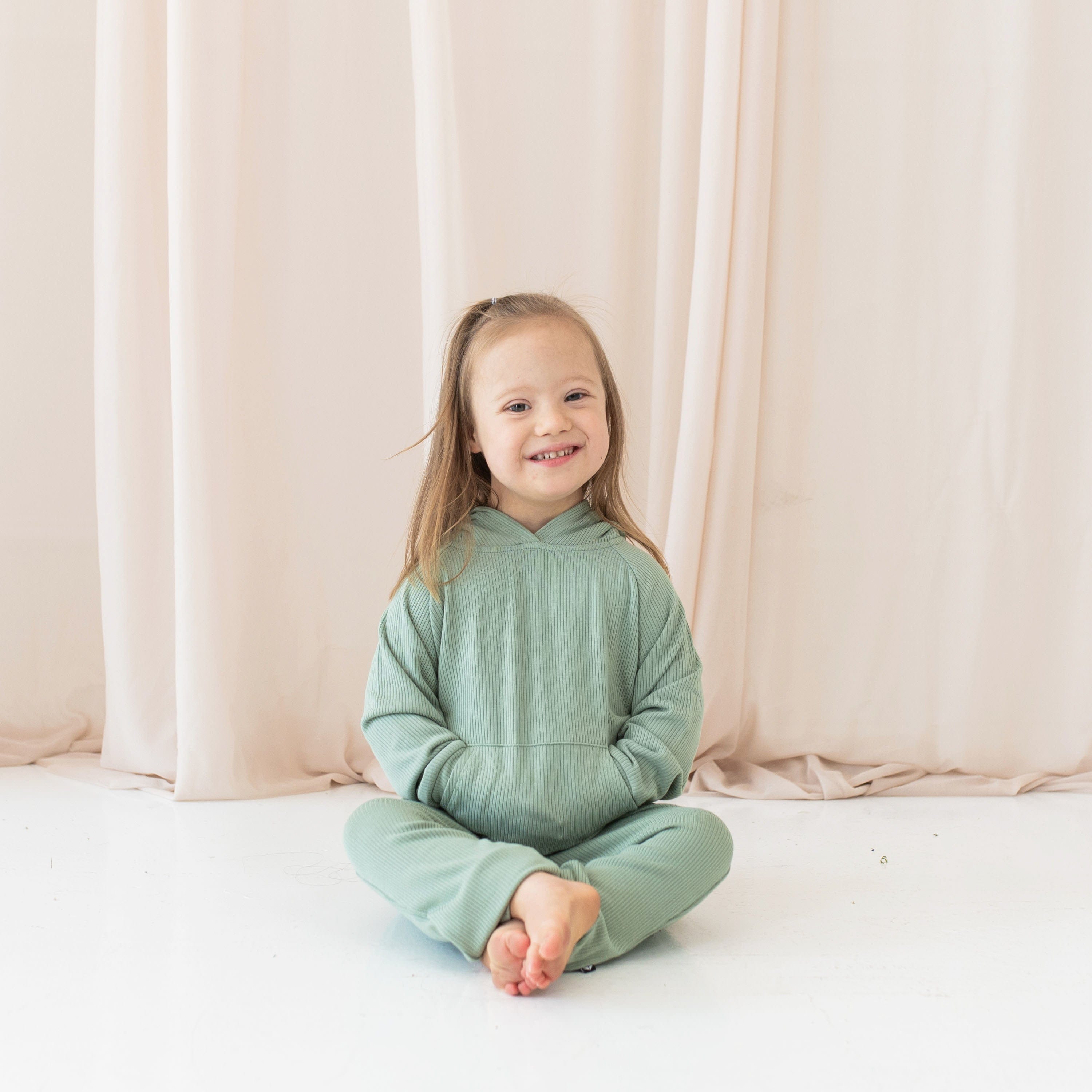 Girl wearing Kyte Baby Ribbed Hoodie and Jogger Pant Set in Thyme