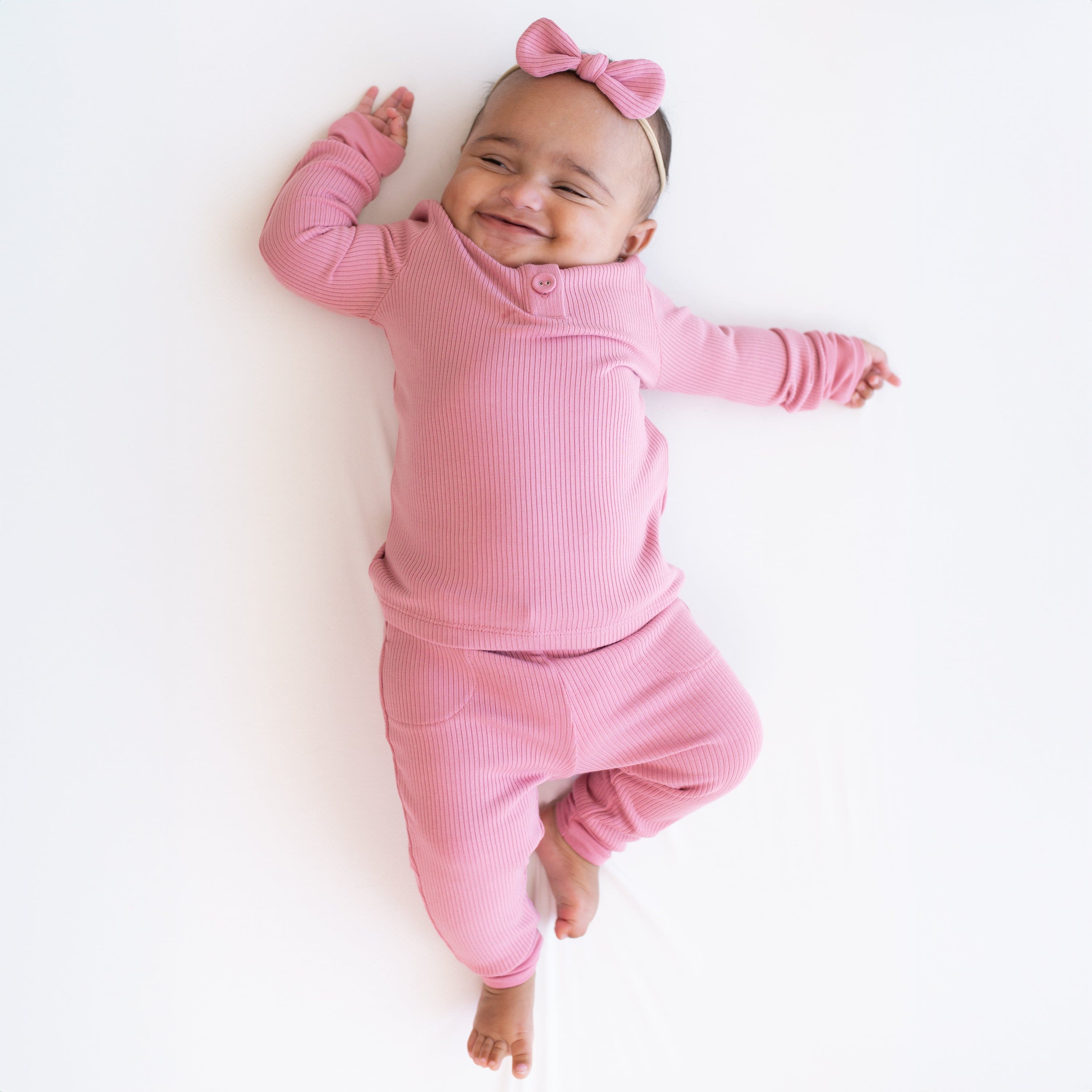 Child wearing Kyte Baby Bamboo Ribbed Infant Henley Set in Apple Blossom pink