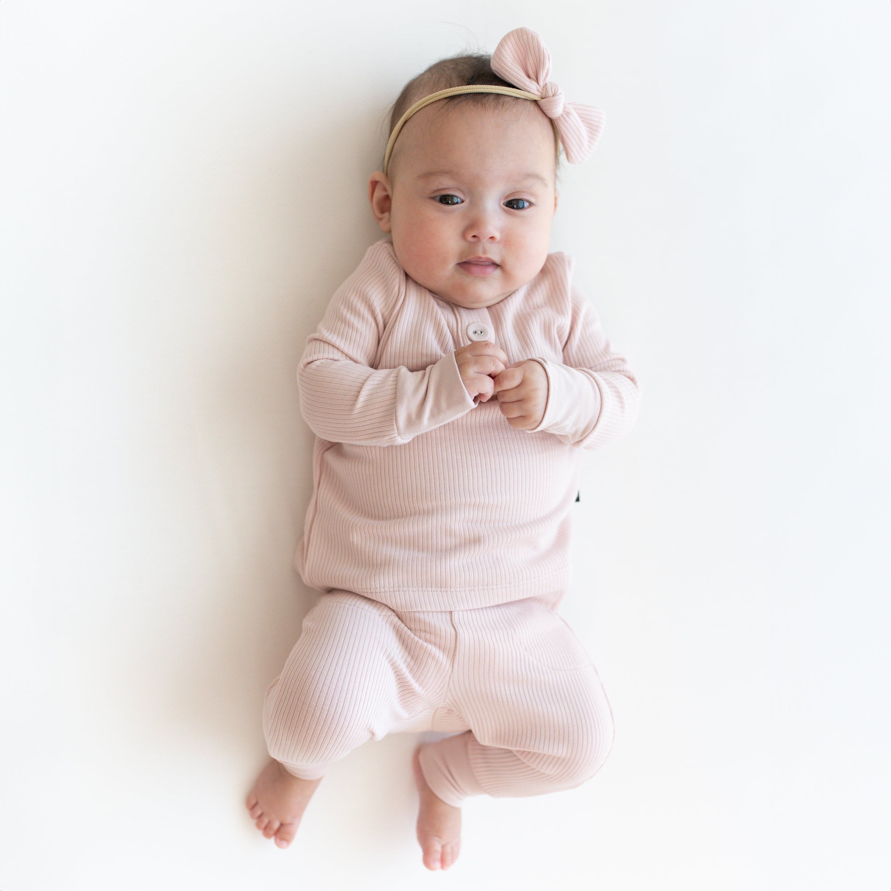 Child wearing Kyte Baby Bamboo Ribbed Infant Henley Set in Blush pink