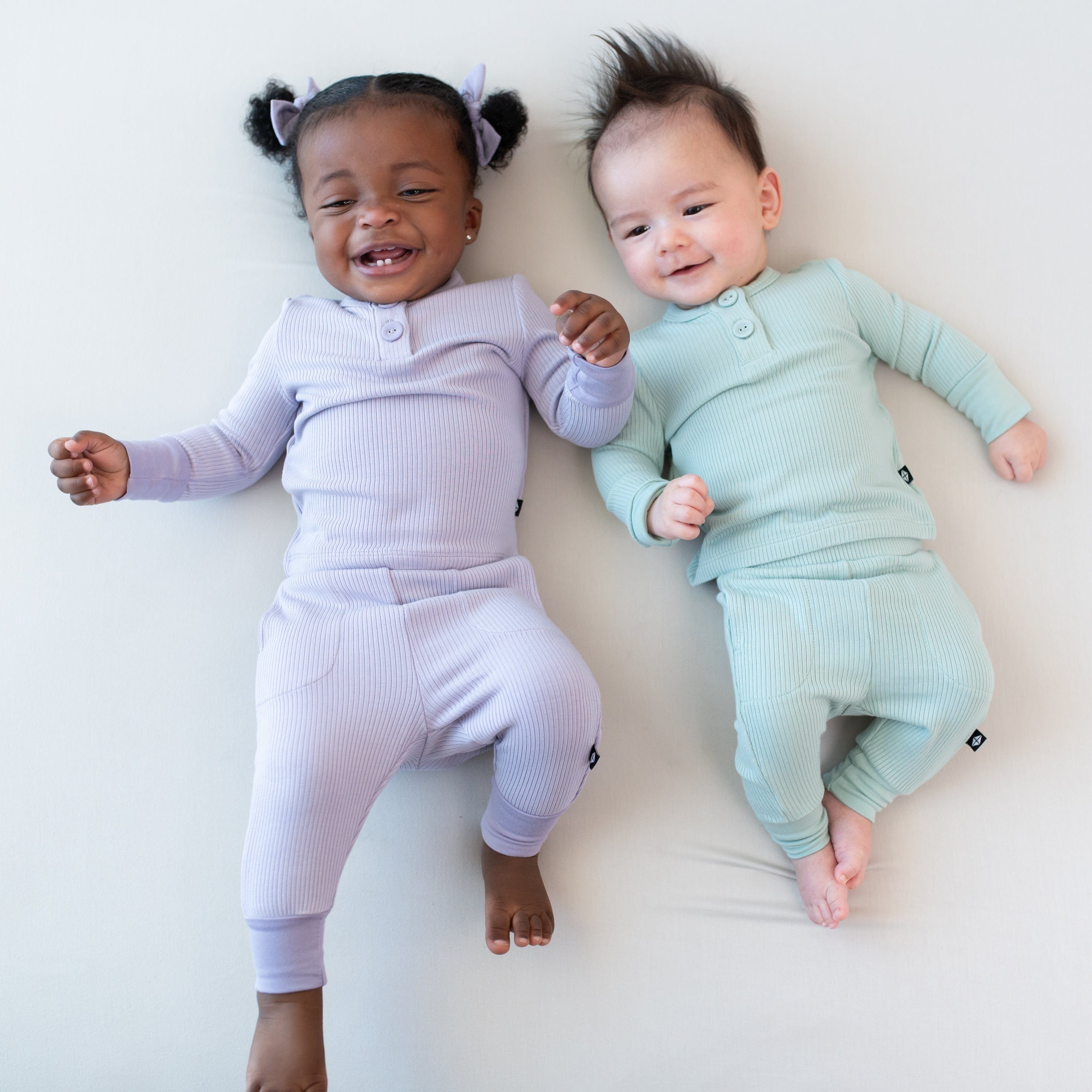Babies wearing Kyte Baby Ribbed Infant Henley Pajama Sets