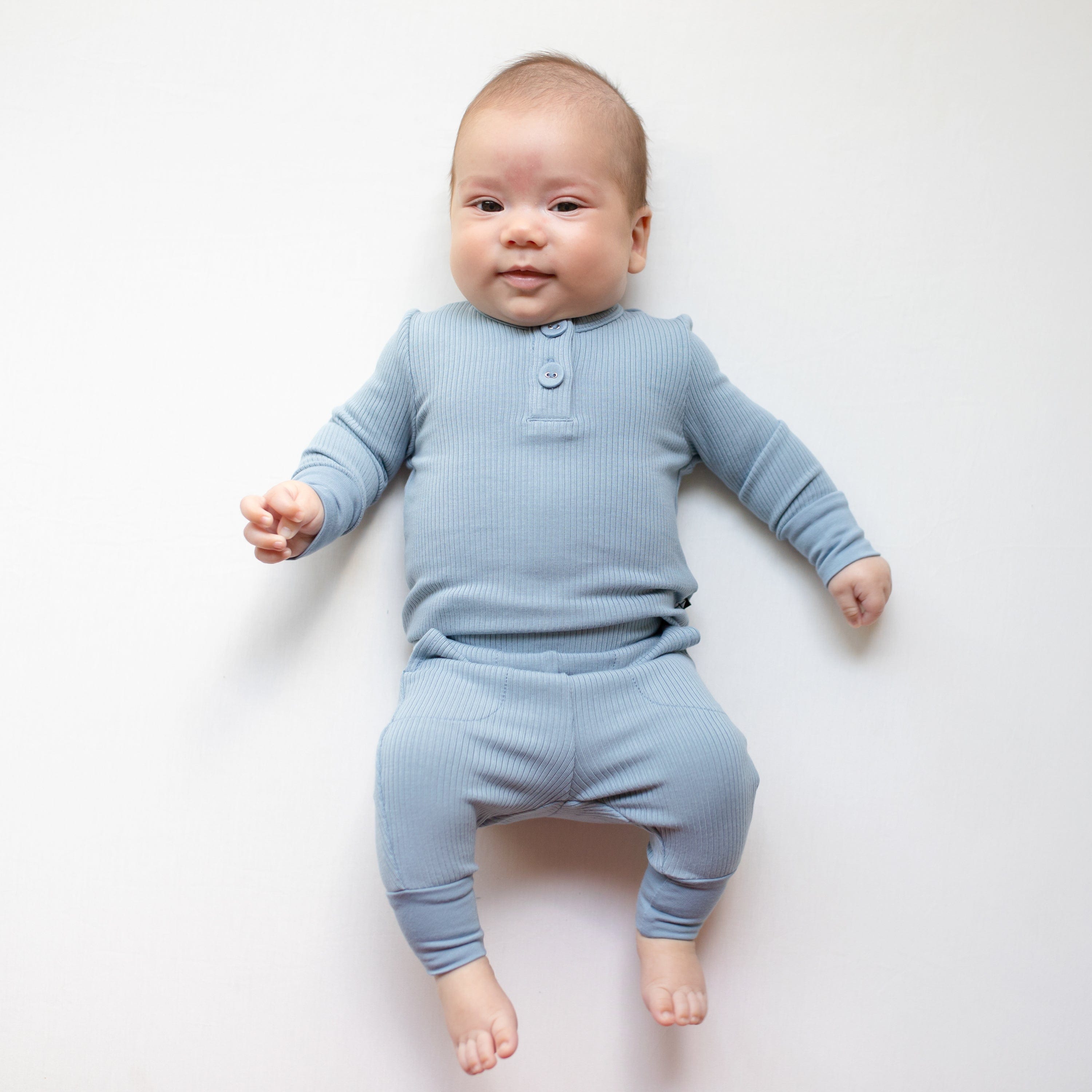 Newborn wearing Kyte Baby Ribbed Infant Henley pajama Set in Slate blue