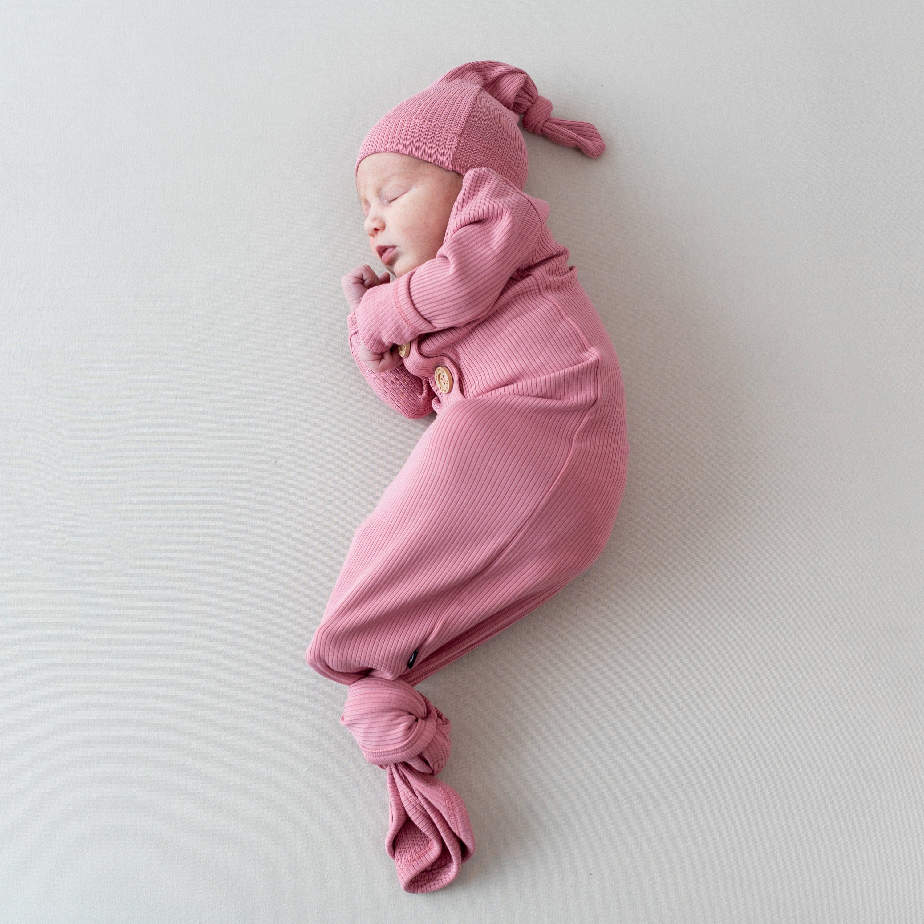 Newborn wearing Kyte Baby bamboo Ribbed Knotted Gown with Hat Set in Apple Blossom