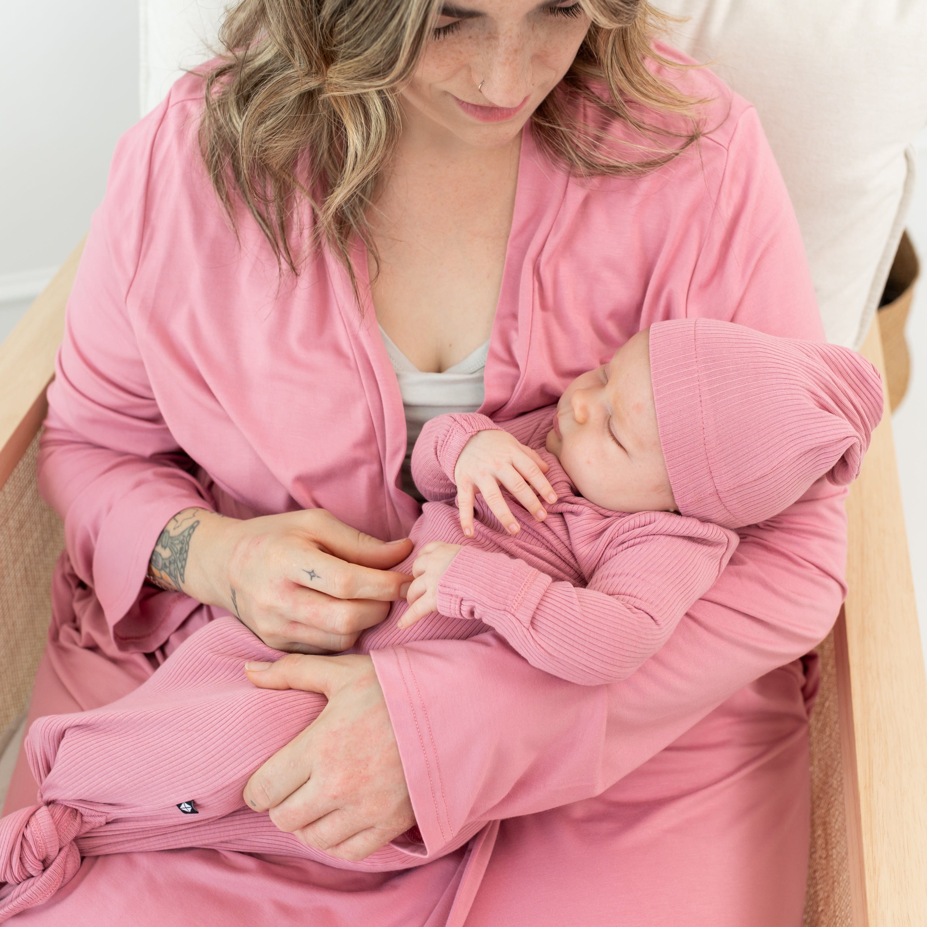Mom holding newborn wearing Kyte Baby Ribbed Knotted Gown with Hat Set in Apple Blossom