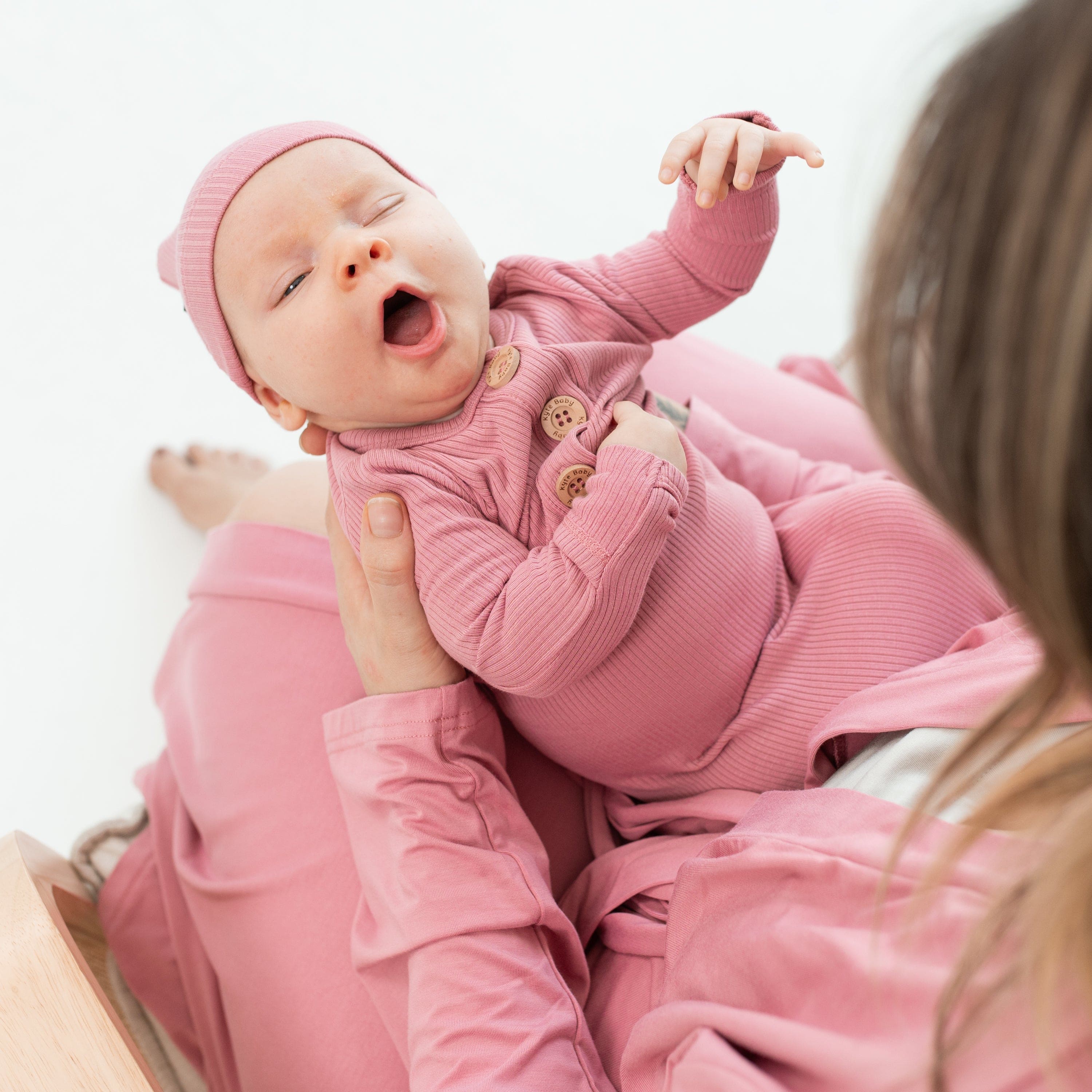 Newborn wearing Kyte Baby Ribbed Knotted Gown with Hat Set in Apple Blossom pink