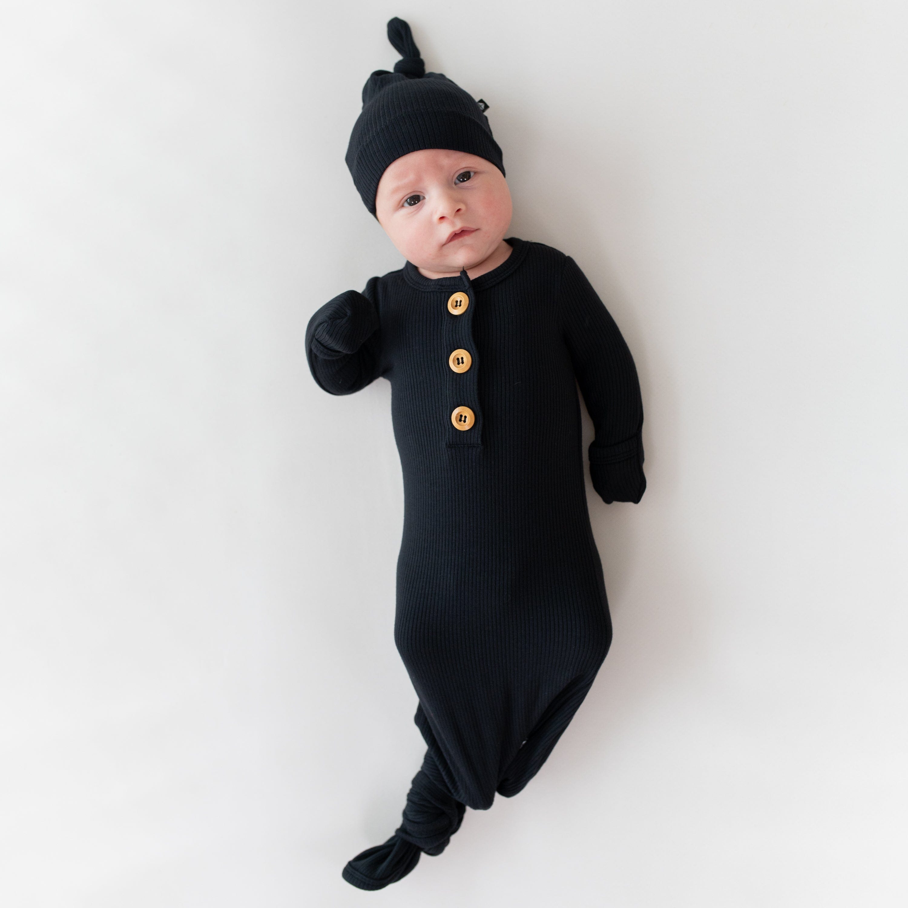 Baby wearing Kyte Baby Ribbed Knotted Gown with Hat Set in Midnight