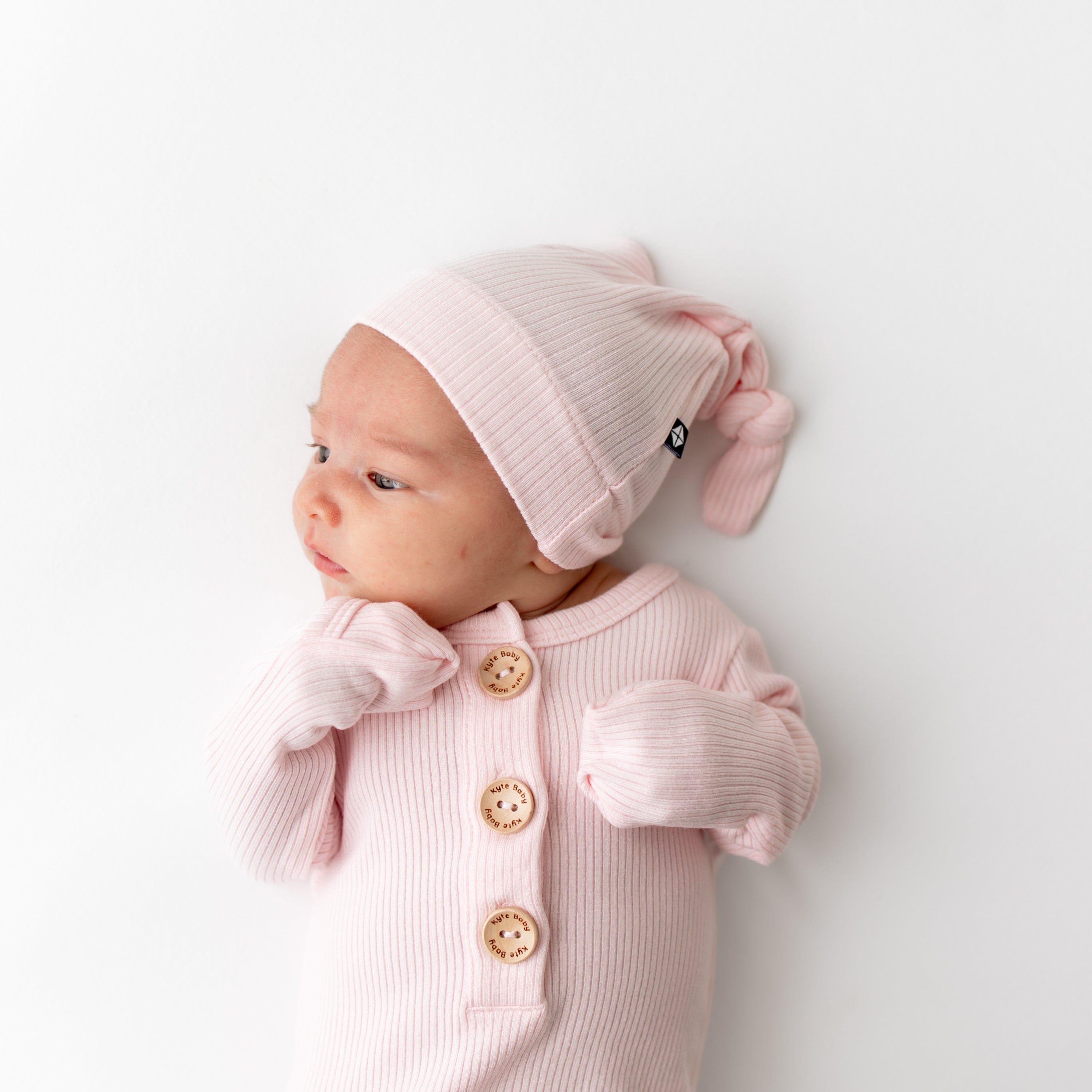 Newborn wearing Kyte Baby Ribbed Knotted Gown with Hat Set in Sakura PInk