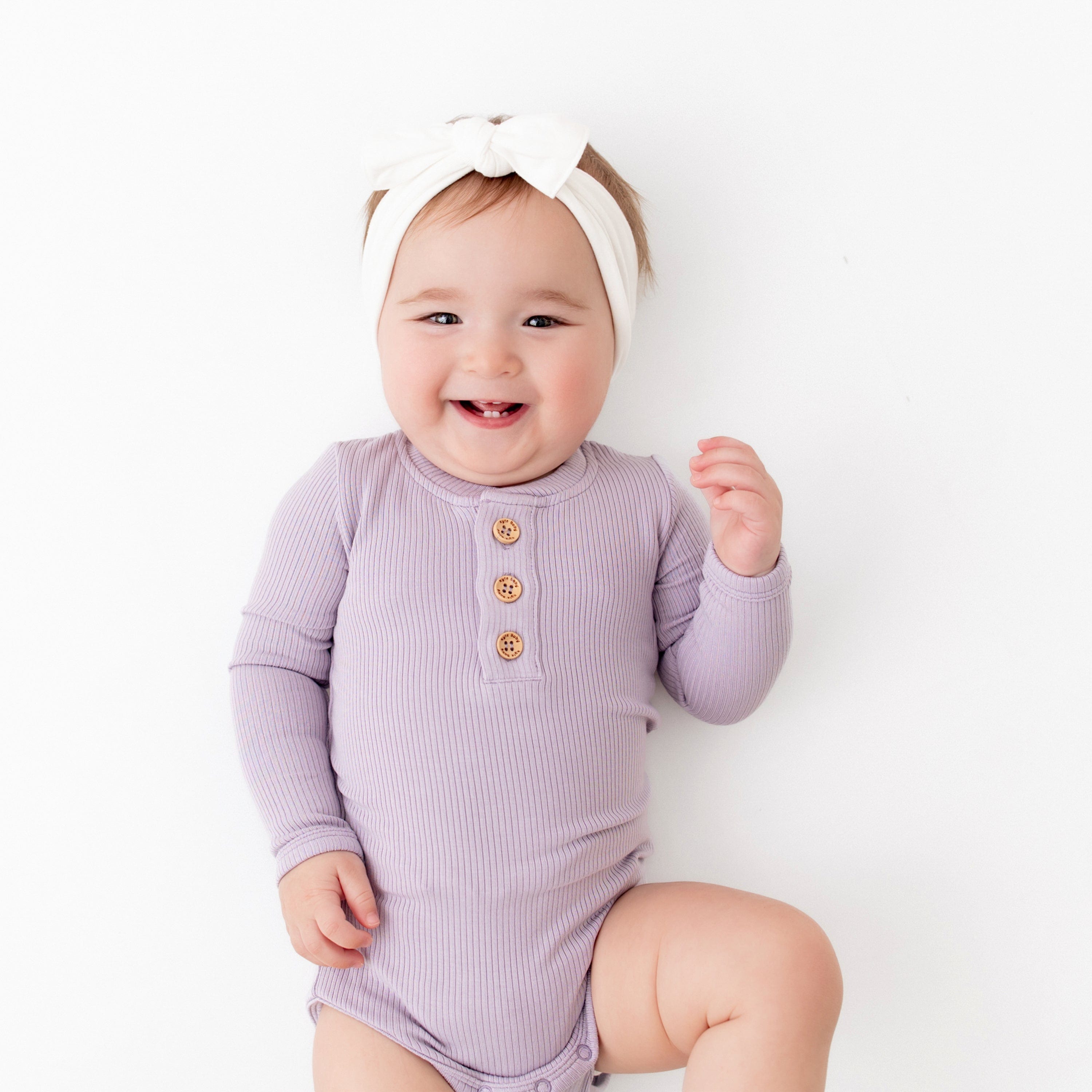 Infant wearing Kyte Baby Ribbed Long Sleeve Henley Bodysuit in Taro