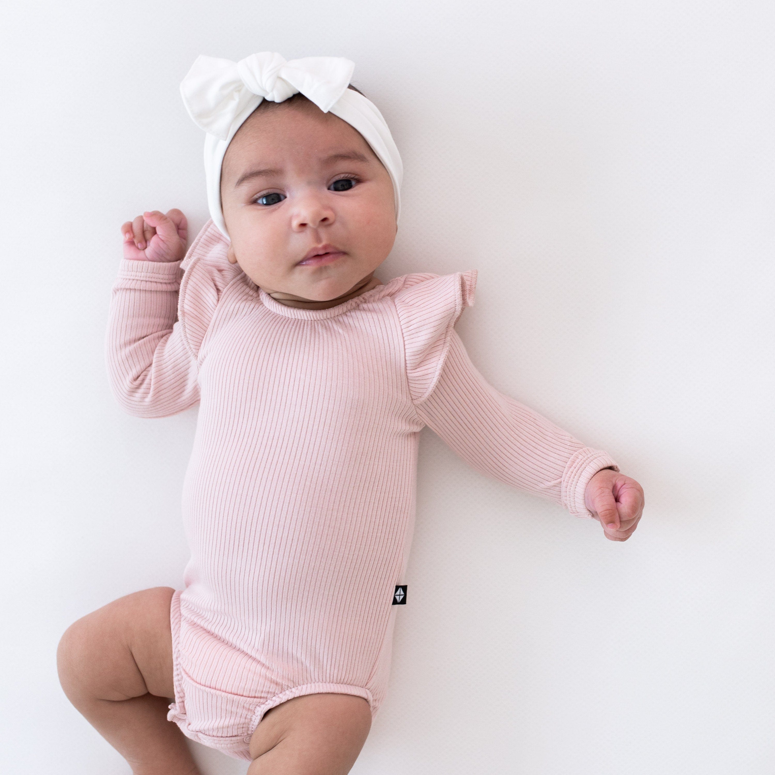 Infant wearing Kyte Baby bamboo Ribbed Long Sleeve Ruffle Leotard in Blush