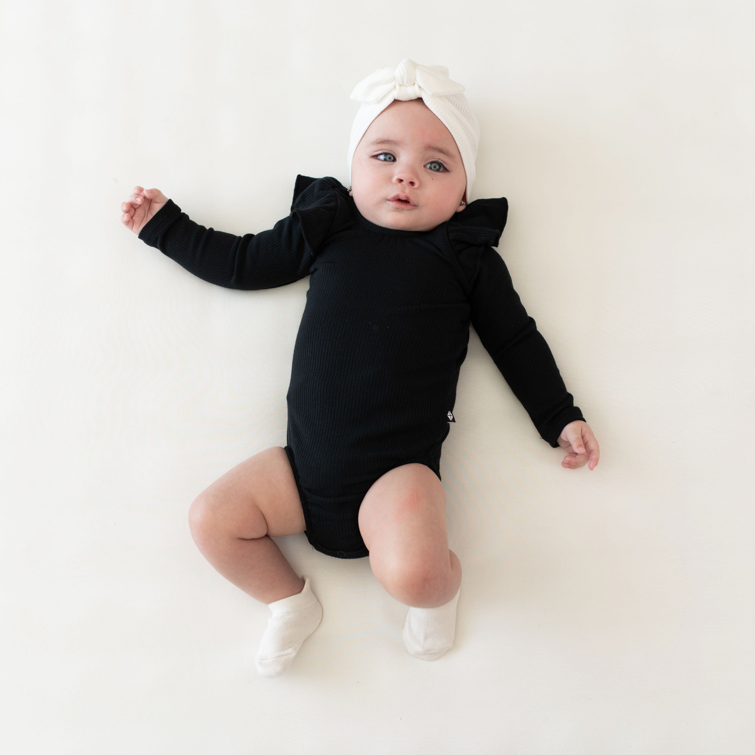 Infant wearing Kyte Baby bamboo Ribbed Long Sleeve Ruffle Leotard in Midnight