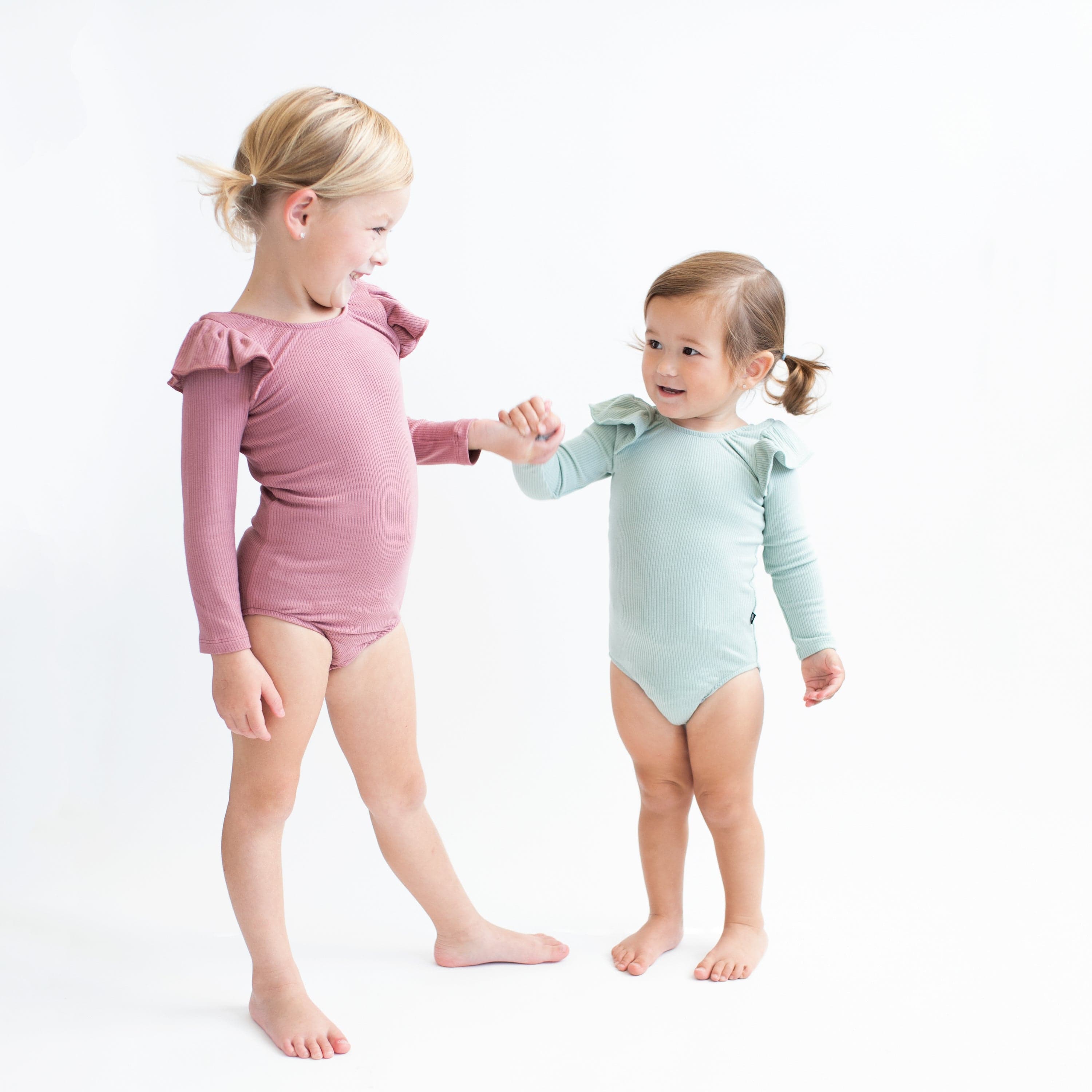 Children wearing Kyte Baby Ribbed Long Sleeve Ruffle Leotards