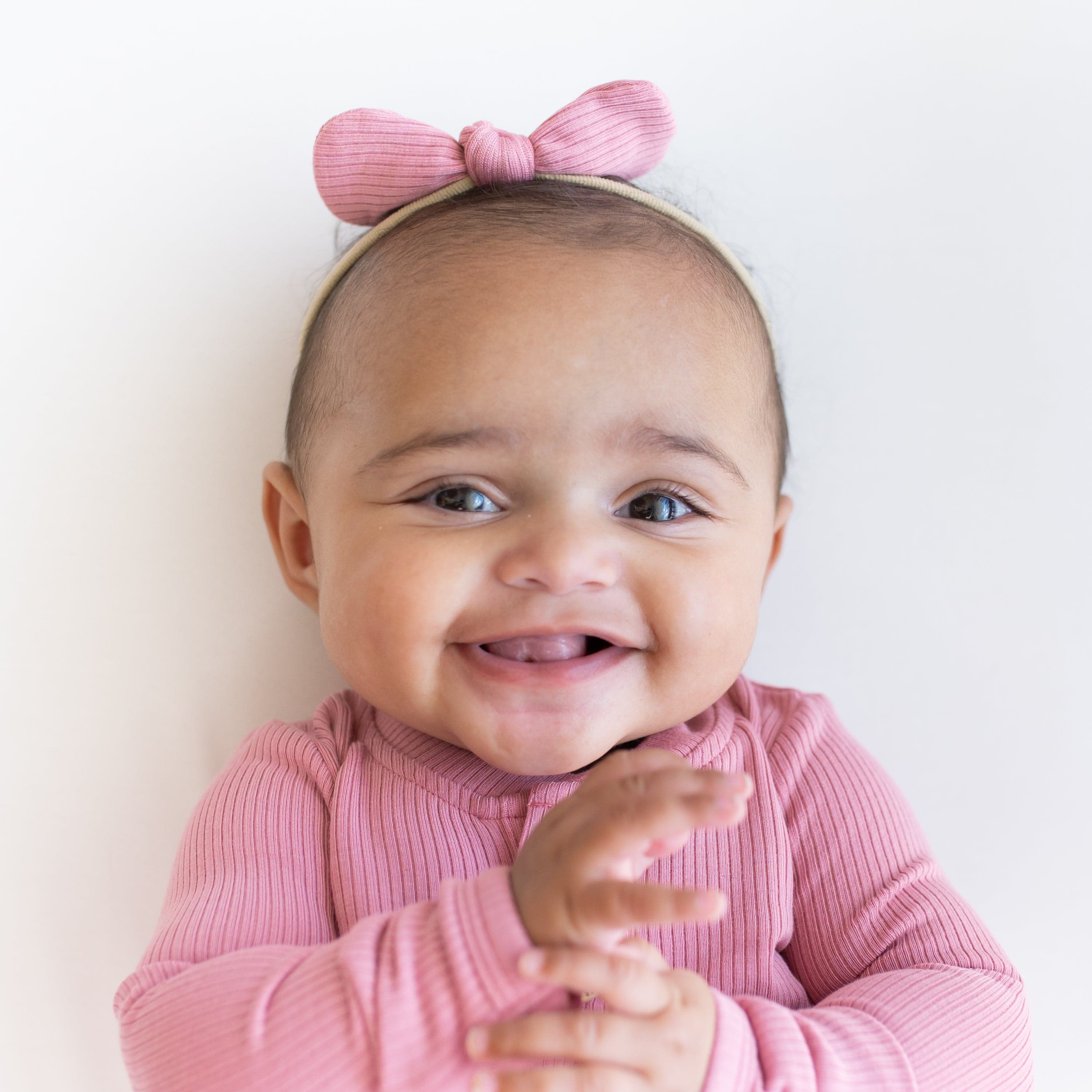 Infant wearing Kyte Baby Ribbed Nylon Bow in Apple Blossom