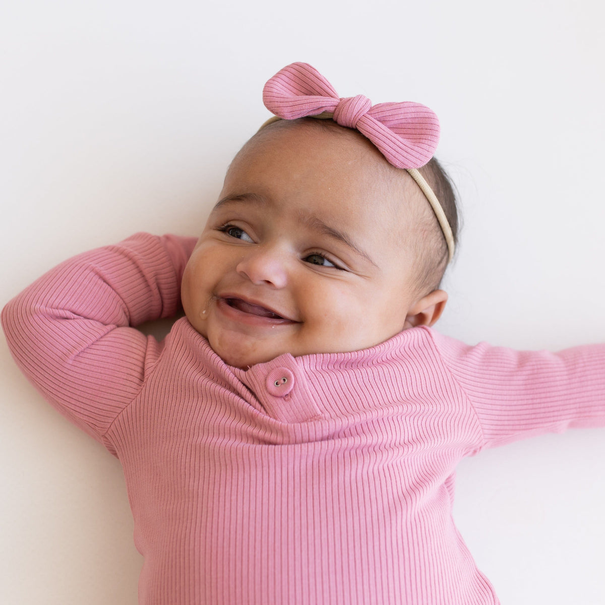 Infant wearing Kyte Baby Ribbed Bow with Nylon Band in Apple Blossom pink