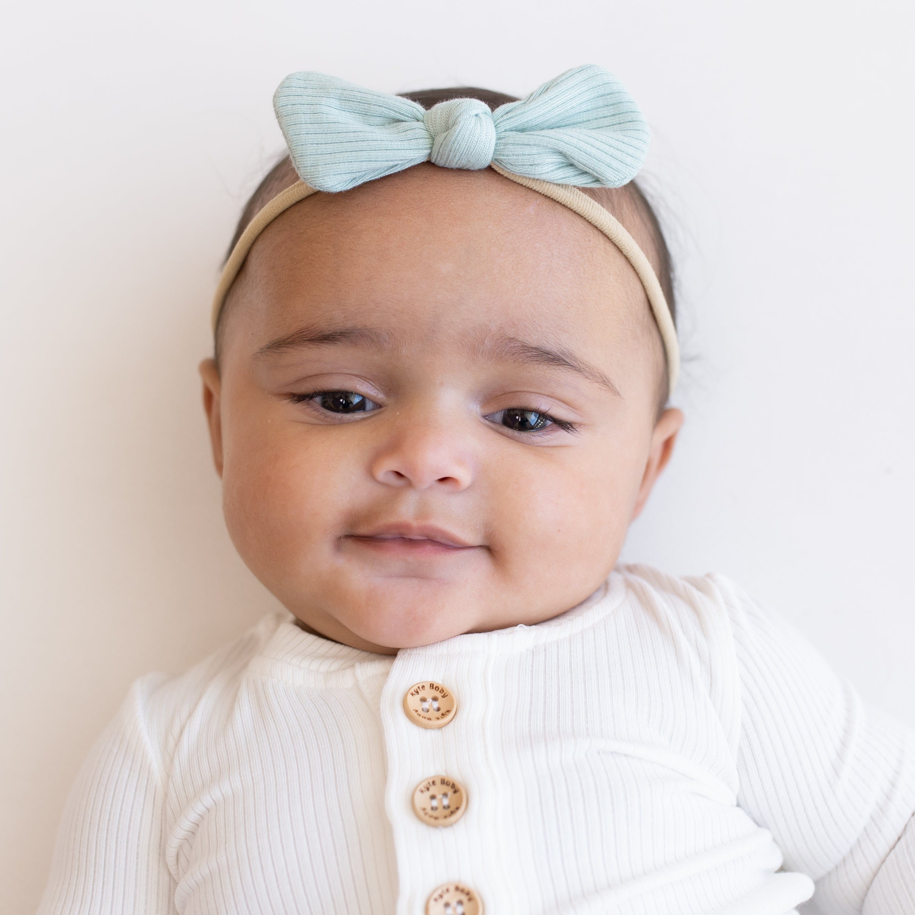 Infant wearing Kyte Baby Ribbed Nylon Bow in Sage