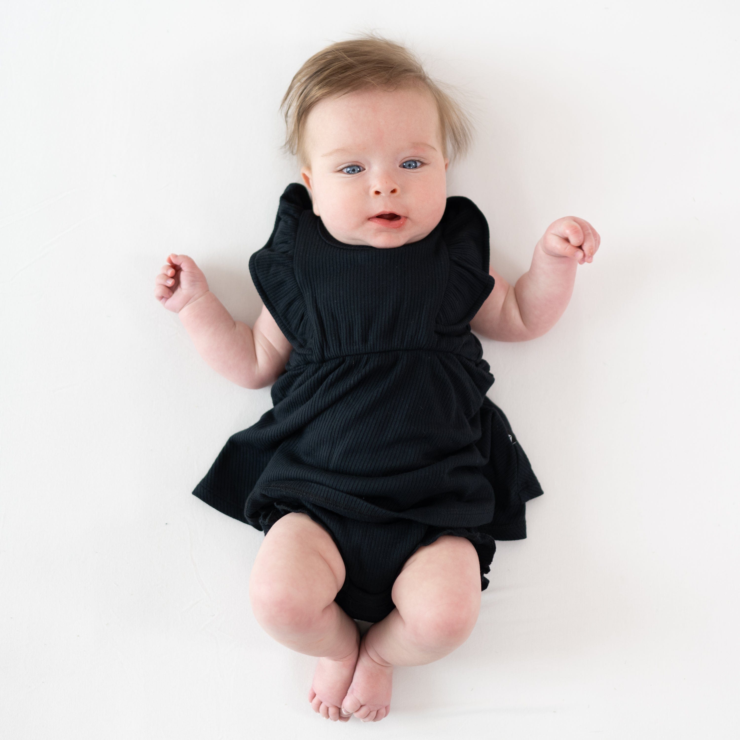 Infant wearing Kyte Baby Ribbed Peplum Dress Set in Midnight black
