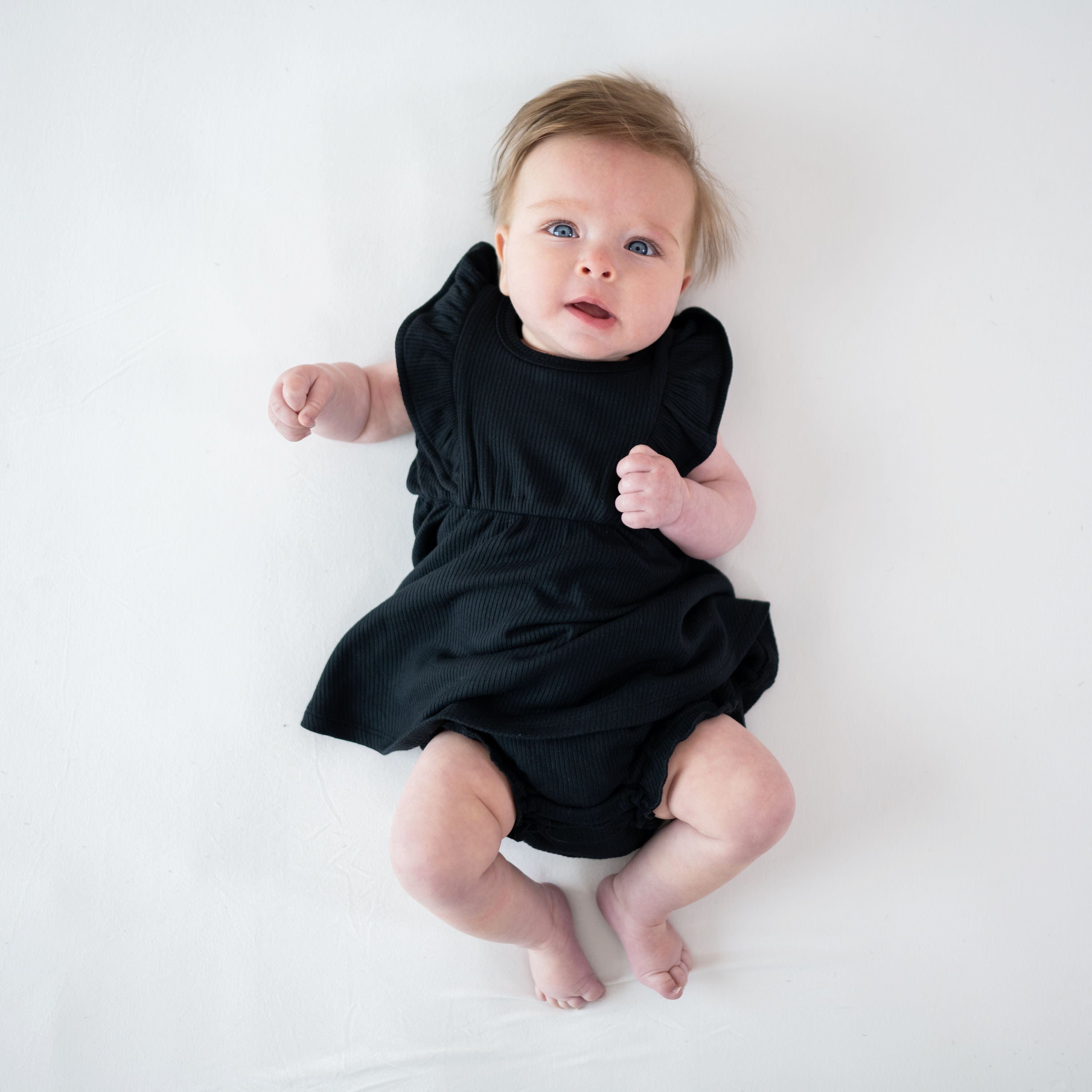 Infant wearing Kyte Baby Ribbed Peplum Dress Set with Flutter Sleeves in Midnight