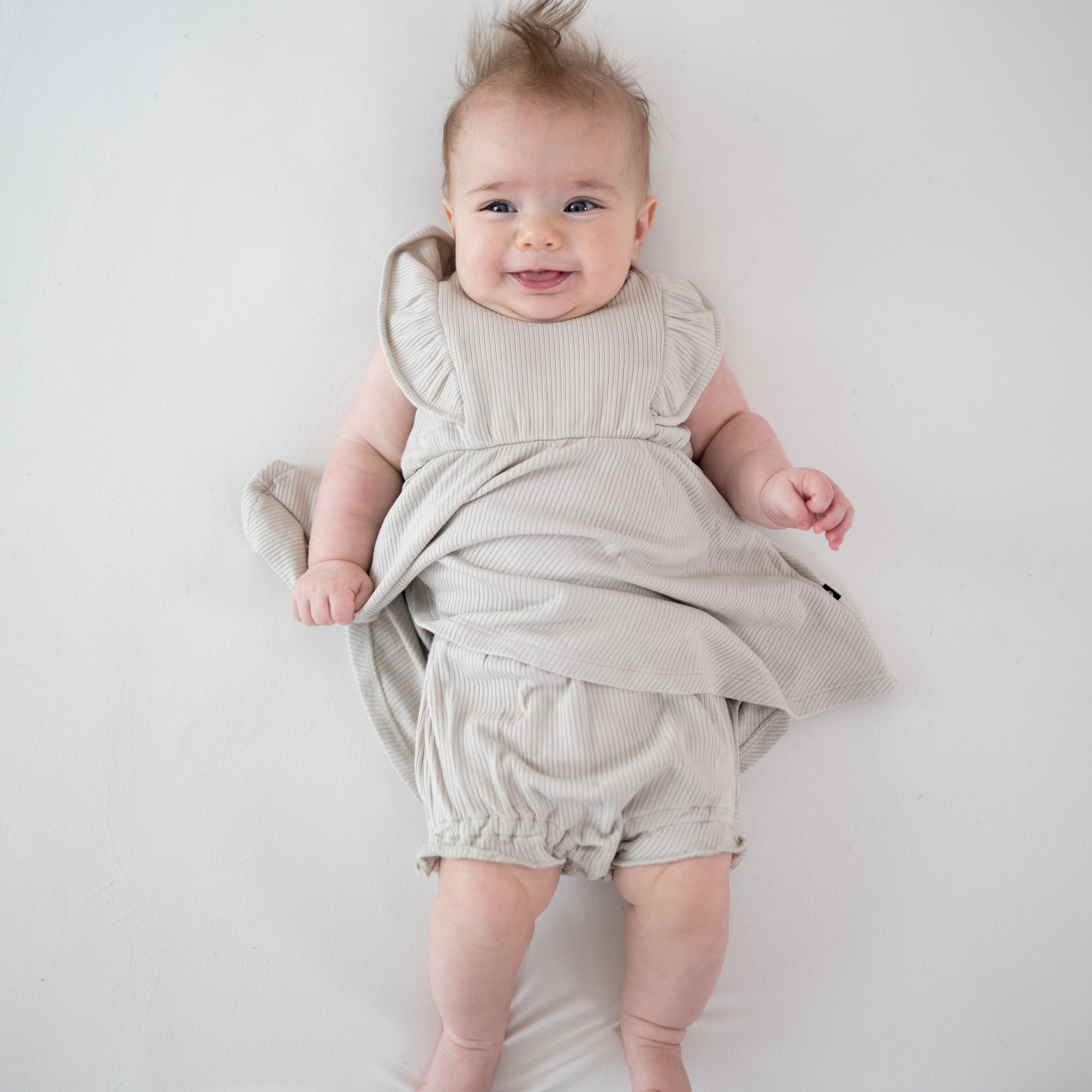 Infant wearing Kyte Baby Ribbed Peplum Dress Set in Oat