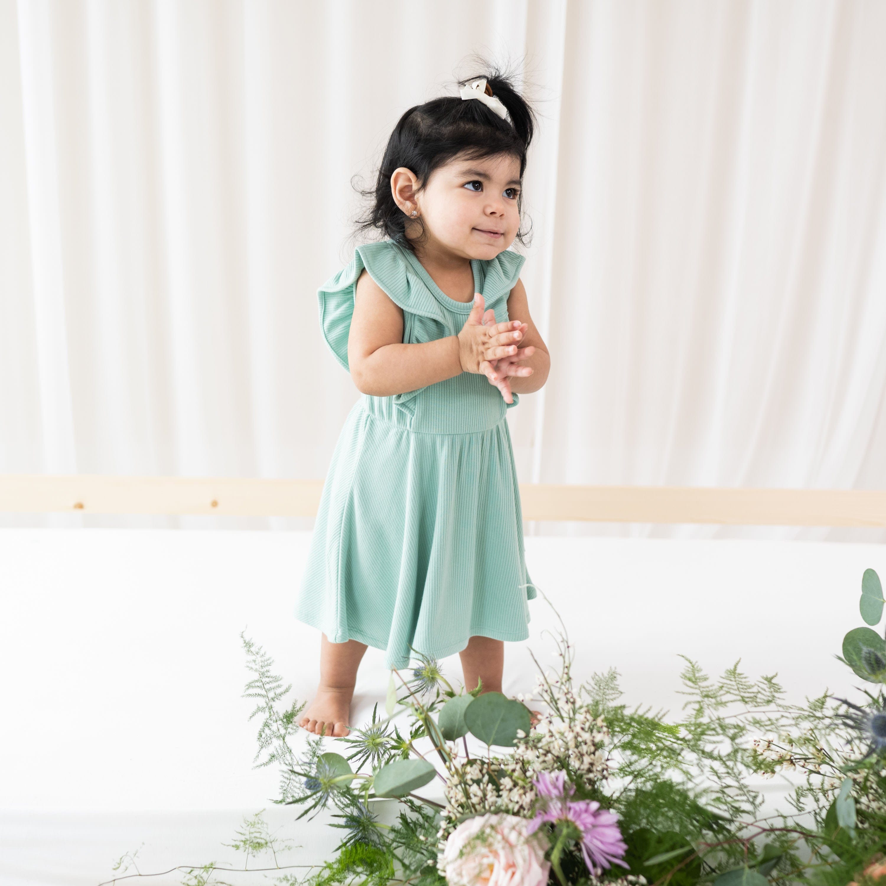 Girl wearing Kyte Baby Ribbed Peplum Dress Set with Flutter Sleeves in Wasabi