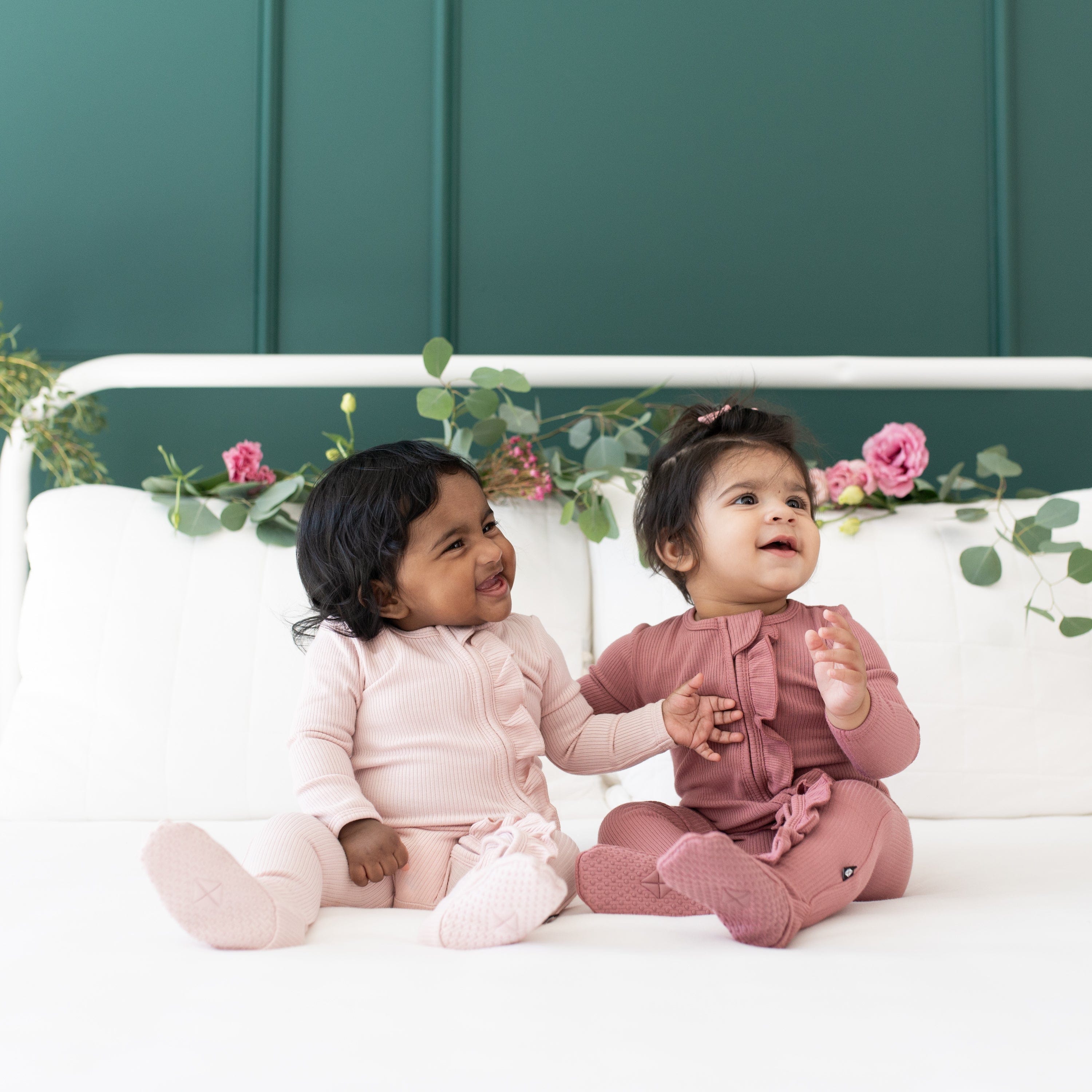 Babies wearing Kyte Baby Ribbed Ruffle Zippered Footie pajamas