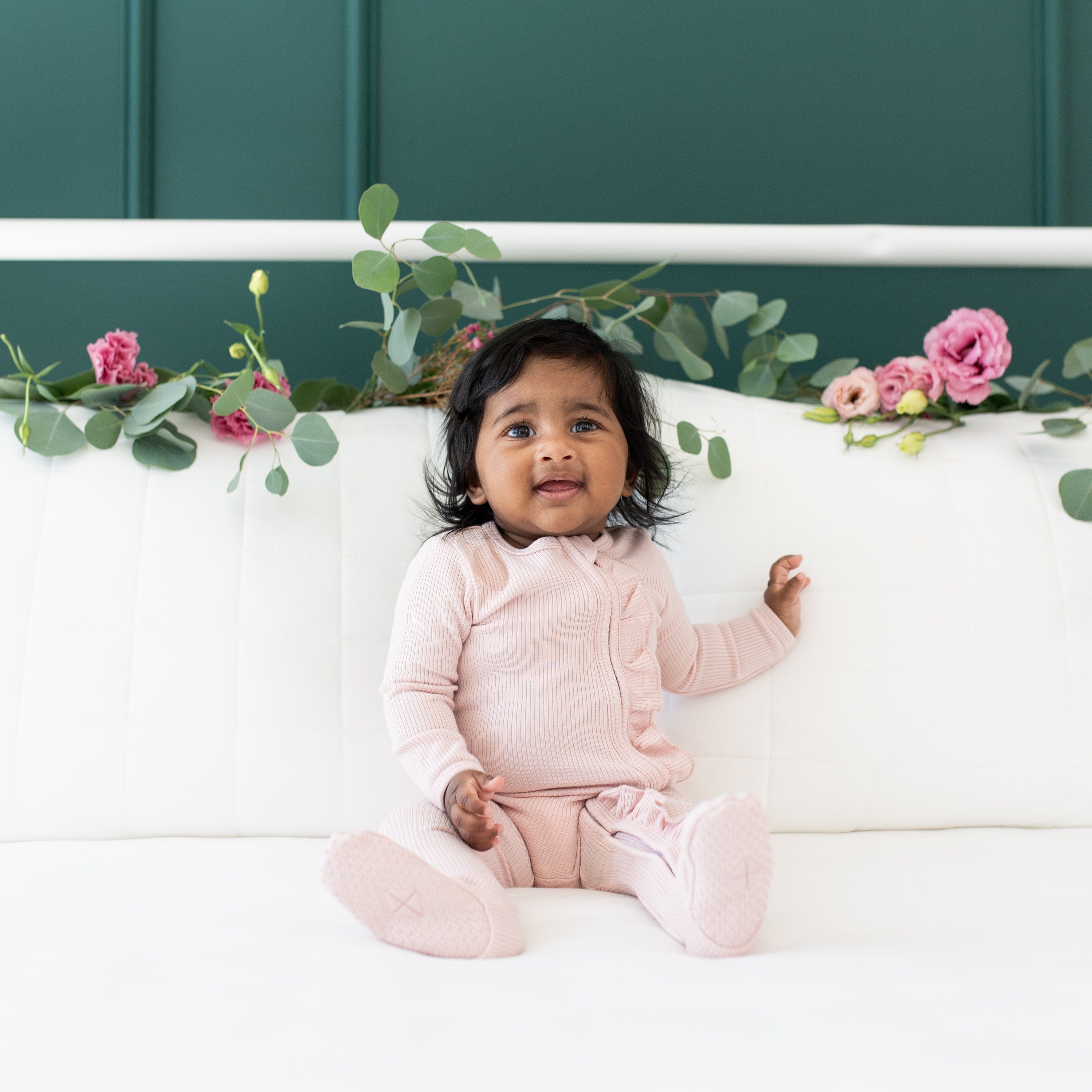 Infant wearing Kyte Baby Ribbed Ruffle Zippered Footie Pajamas in Blush