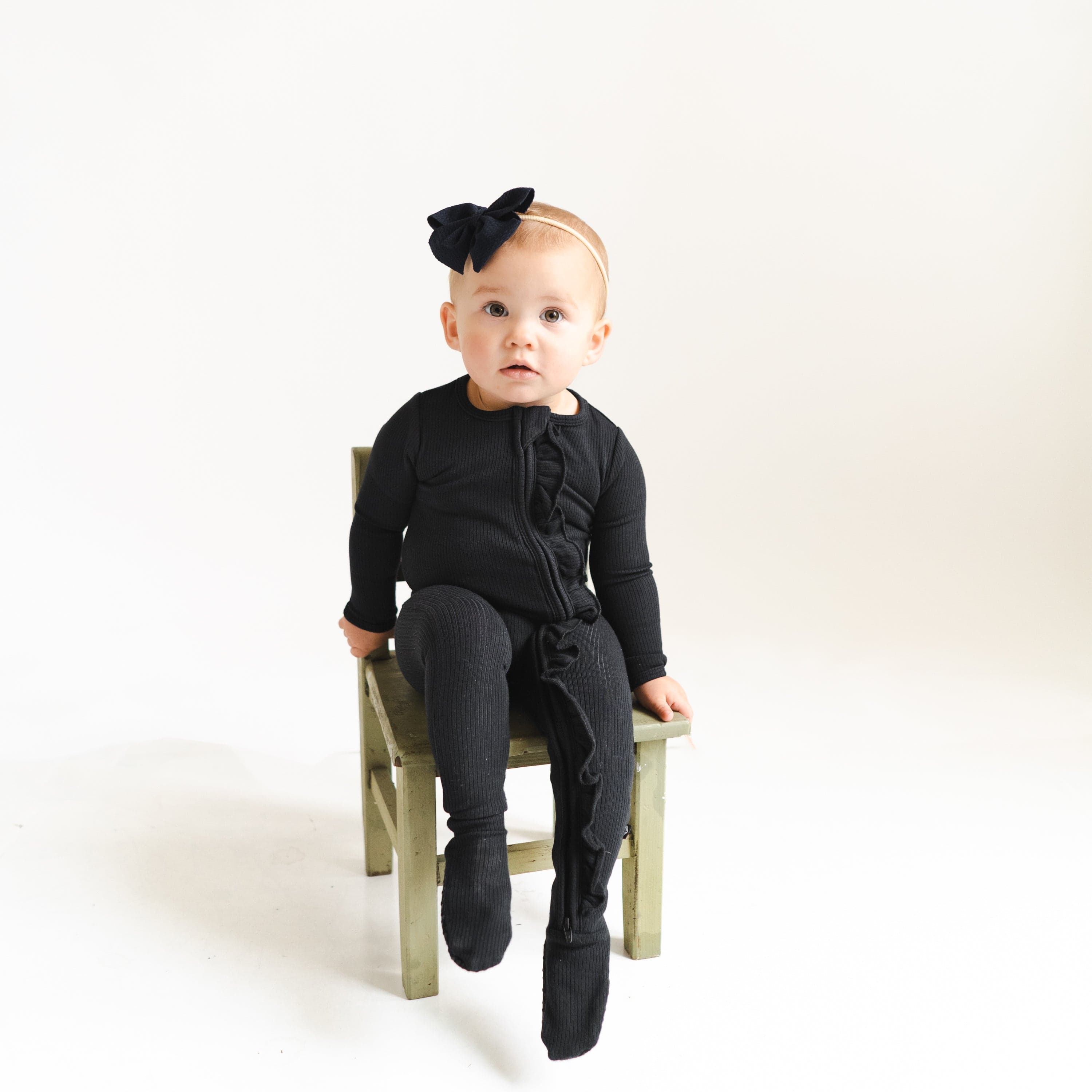 Toddler wearing Kyte Baby Ribbed Zipper Footie with Ruffle in Midnight