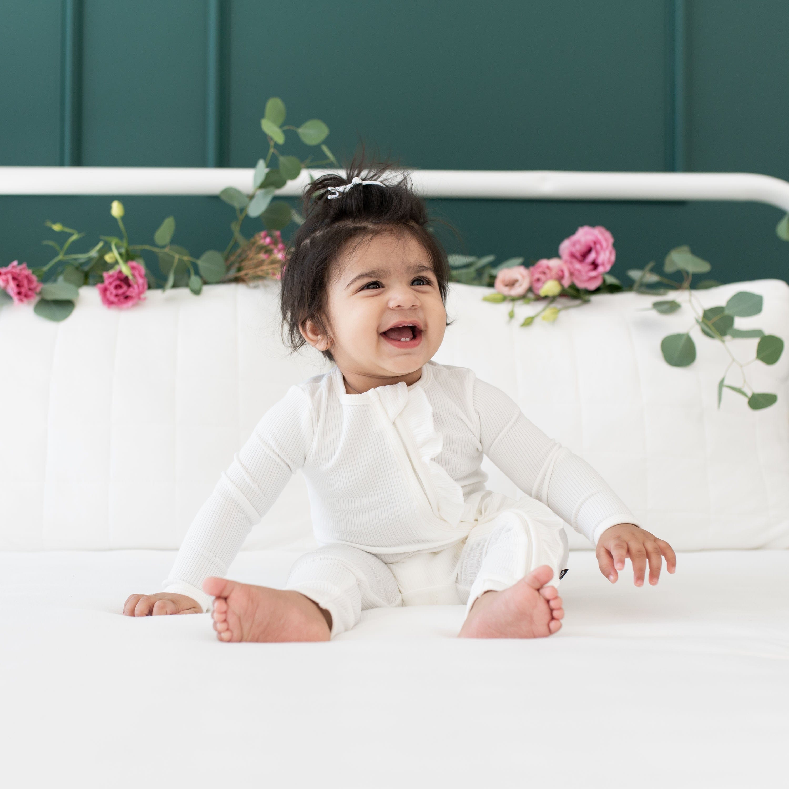 Girl wearing Kyte Baby bamboo Ribbed Ruffle Zipper Romper in Cloud