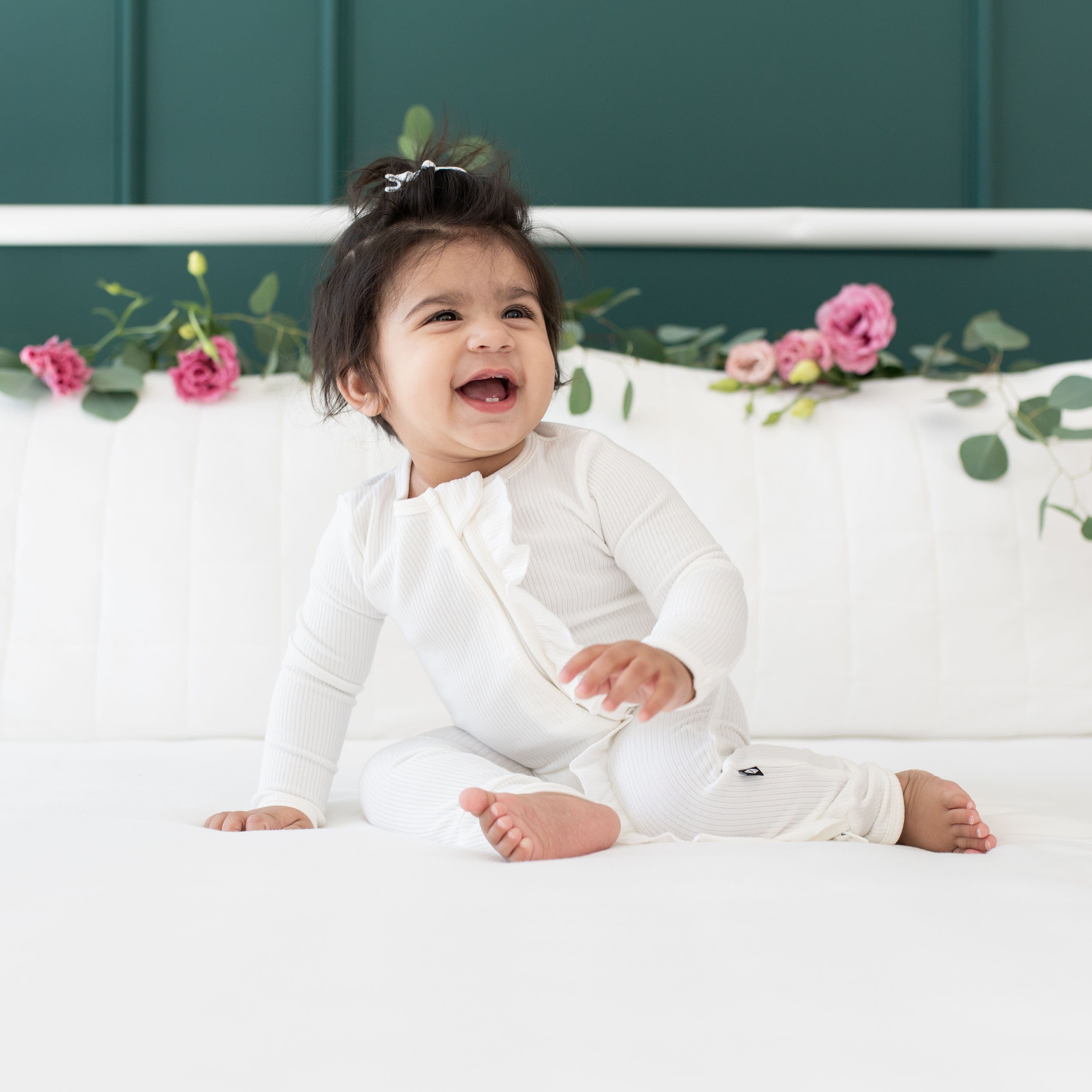 Toddler wearing Kyte Baby Ribbed Ruffle Zipper Romper in Cloud