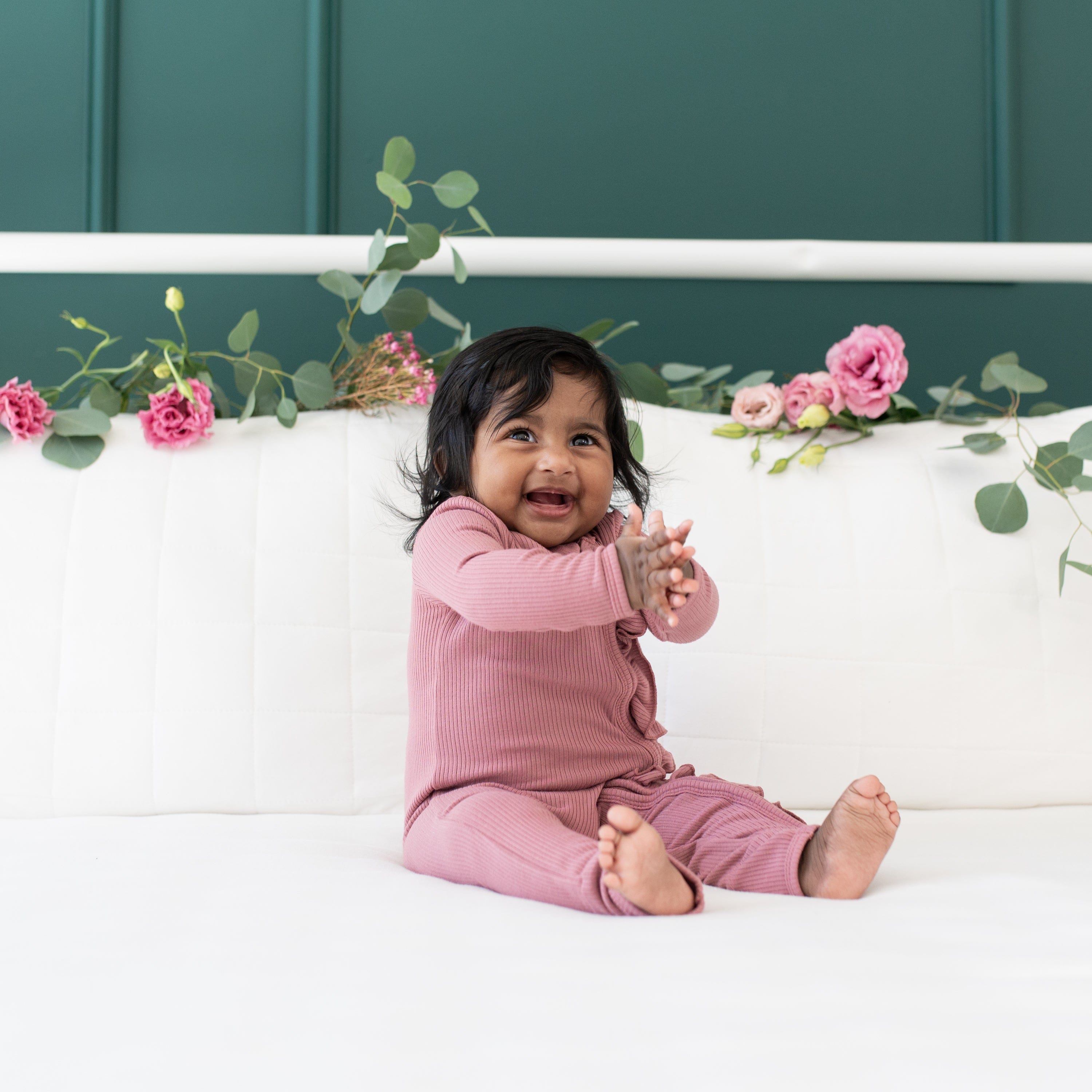 Girl wearing Kyte Baby bamboo Ribbed Ruffle Zipper Romper in Dusty Rose